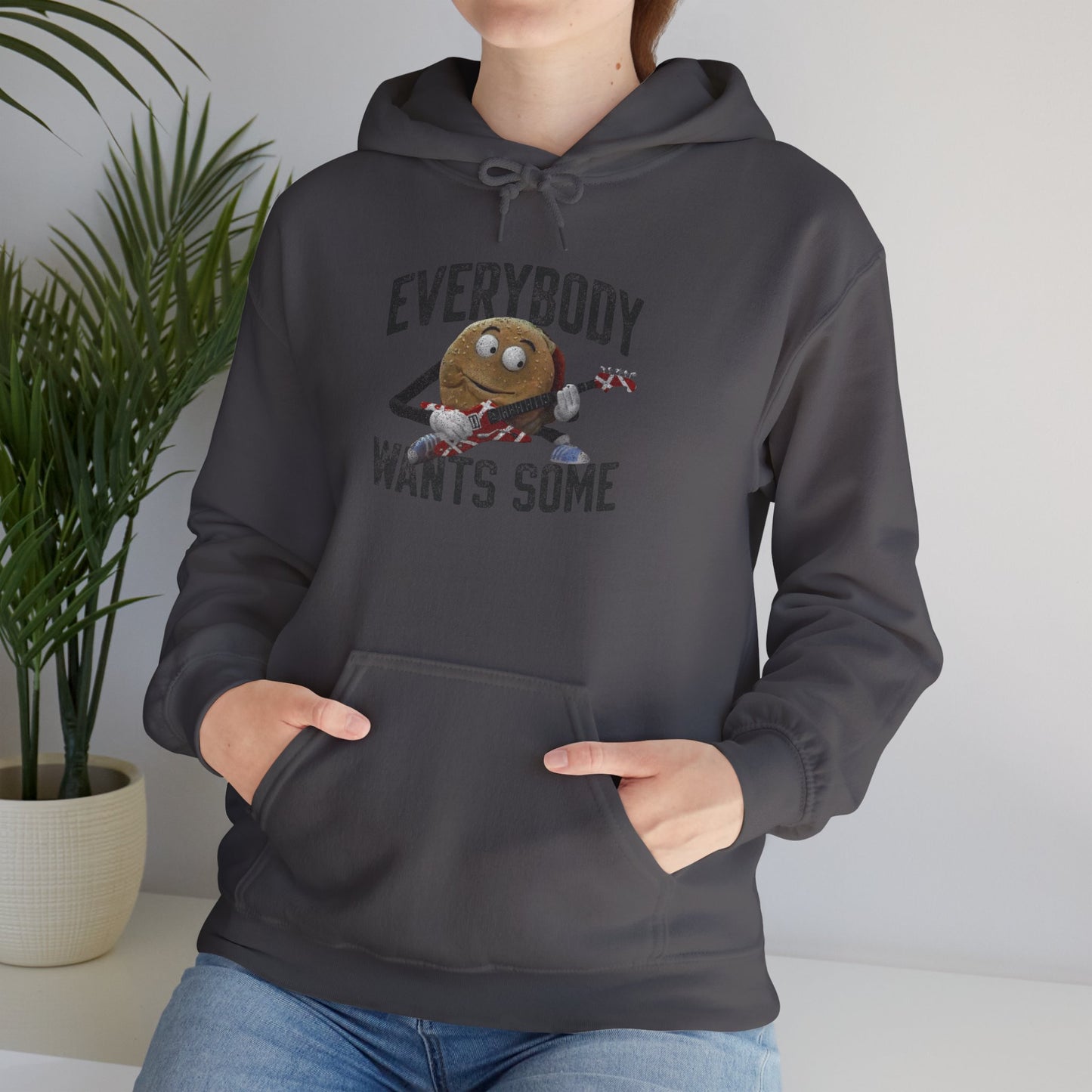 Female model wearing a charcoal grey colored soft Unisex Hoodie Heavy Blend Hooded Sweatshirt featuring the phrase EVERYBODY WANTS SOME with a graphic of the Van Halen singing hamburger playing guitar from the movie Better Off Dead, designed by ScriptedBrand in a vintage distressed style.