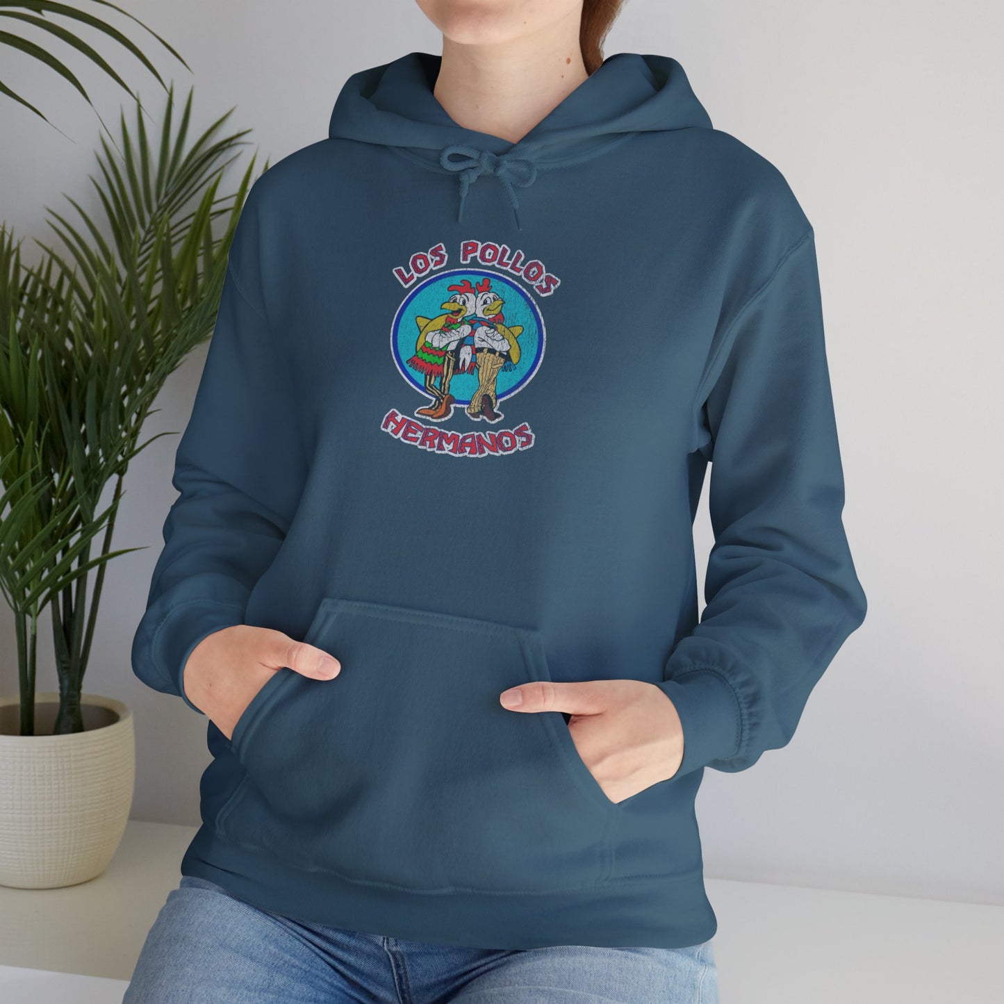 Female model wearing an indigo blue Soft Unisex Hoodie Heavy Blend Hooded Sweatshirt featuring the Los Pollos Hermanos logo from the TV show Breaking Bad and Better Call Saul in a vintage distressed style. Logo is printed on both front and back of hoodie.