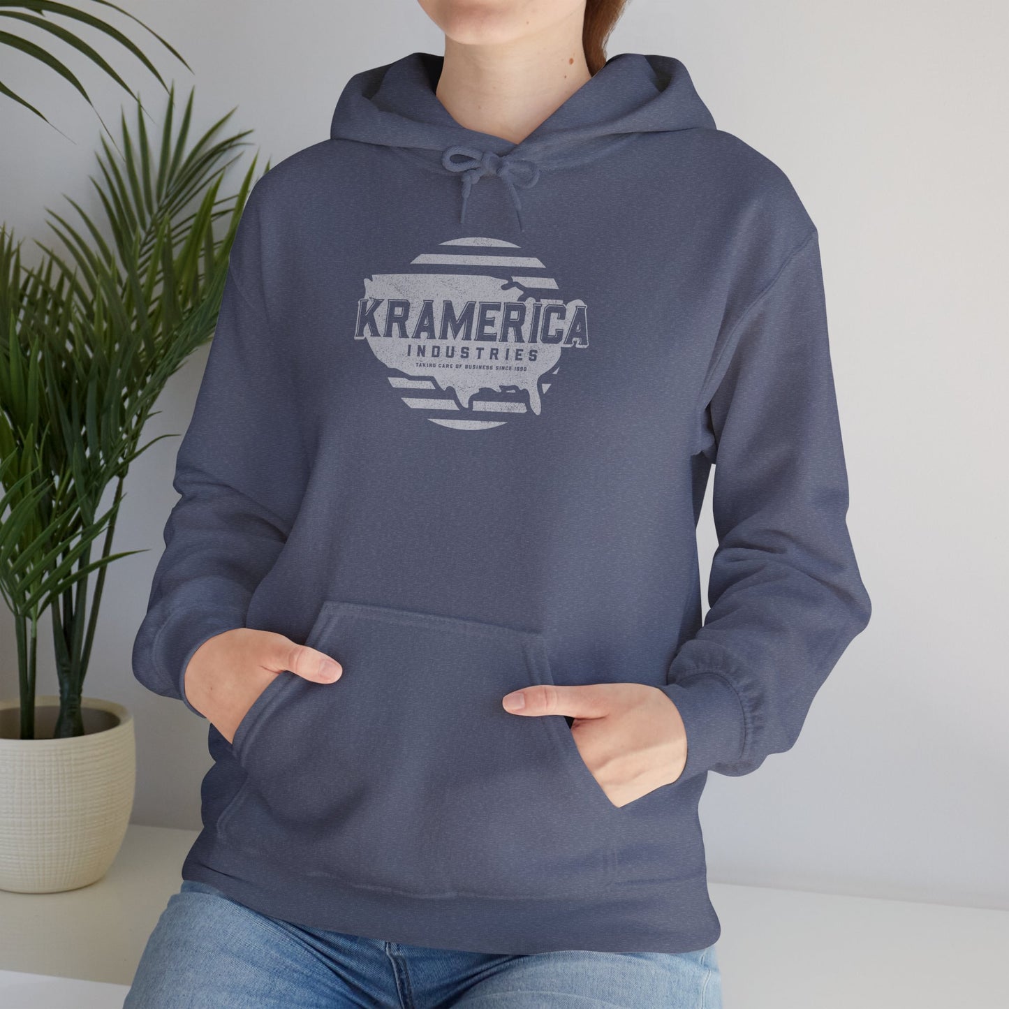 Person wearing Heather Navy Hoodie Sweatshirt featuring a Kramerica logo inspired by Seinfeld, designed by ScriptedBrand in a vintage distressed style.