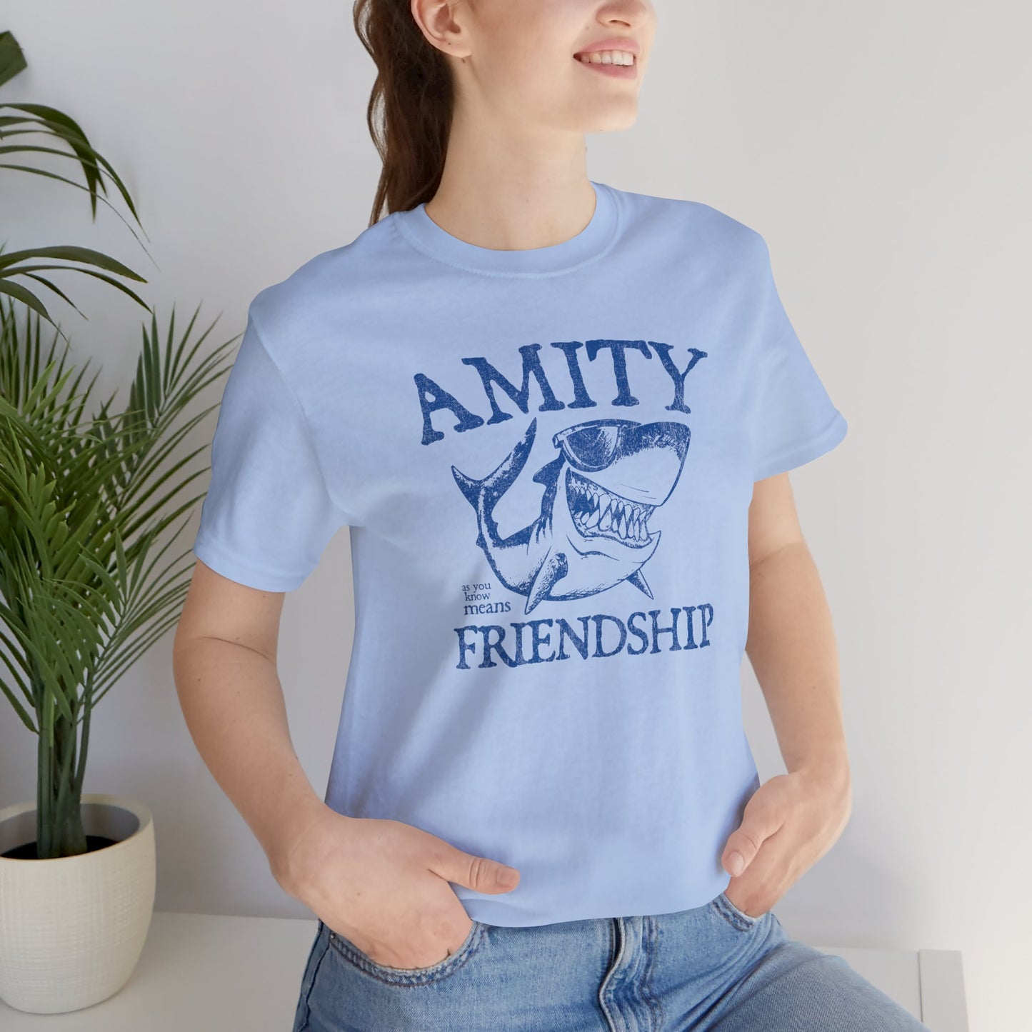 Female wearing blue Bella+Canvas t-shirt with a vintage-style Amity Island “Friendship” shark graphic inspired by the movie Jaws