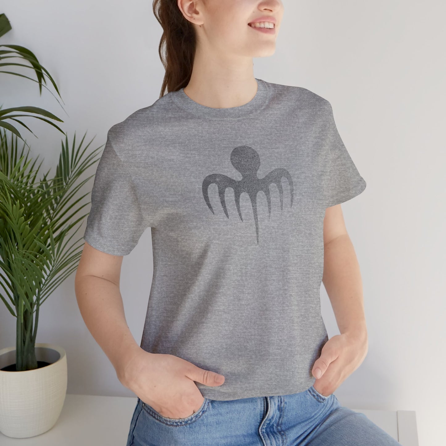 Female model wearing an athletic heather grey colored soft Bella+Canvas 3001 short-sleeve t-shirt featuring a logo graphic of the fictional criminal organization Spectre, inspired by the James Bond movie franchise, in a vintage distressed style.