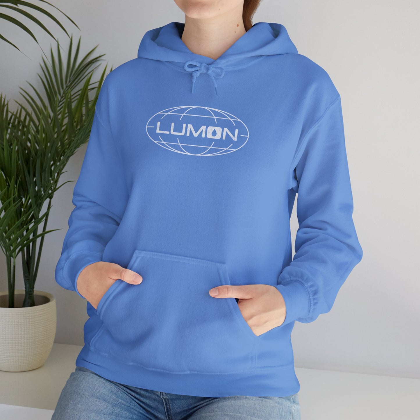 Woman model wearing a Carolina Blue colored Soft Unisex Heavy Blend Hooded Sweatshirt featuring the fictional Lumon Industries logo from the Apple TV show Severance.