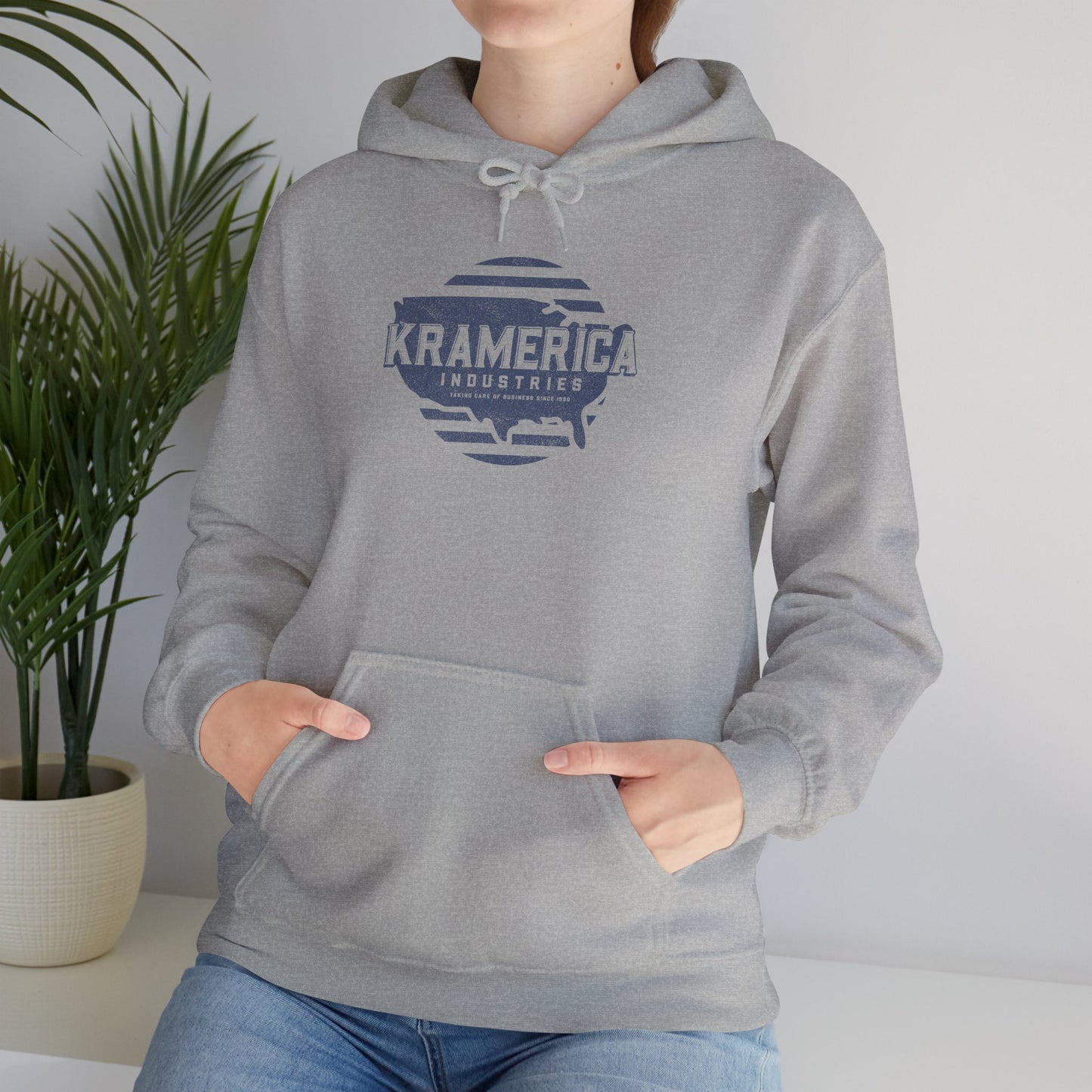 Woman wearing Heather Gray Hoodie Sweatshirt featuring a Kramerica logo inspired by Seinfeld, designed by ScriptedBrand in a vintage distressed style.