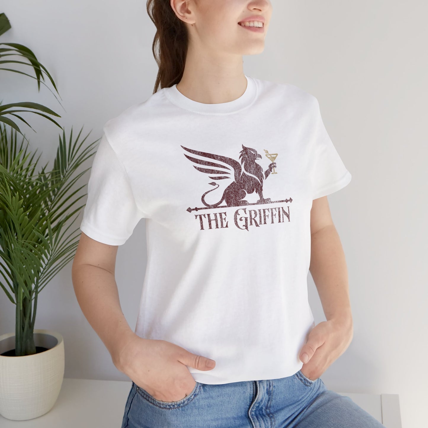 Smiling woman wearing white t-shirt featuring 'The Griffin' Bar logo inspired by the TV show New Girl in a vintage distressed style.