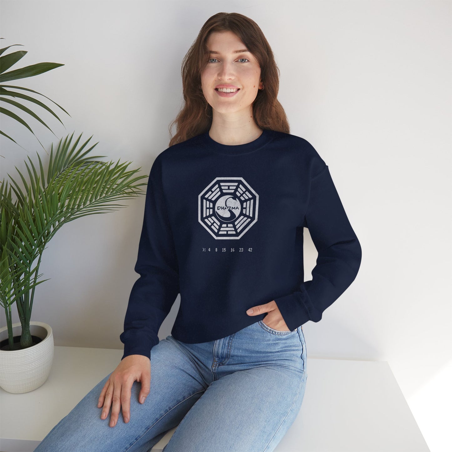 model wearing a navy blue Soft Gildan 18000 crew neck sweatshirt featuring the Dharma Initiative swan logo graphic from the TV show LOST in a vintage distressed ink-stamped worn-in style.
