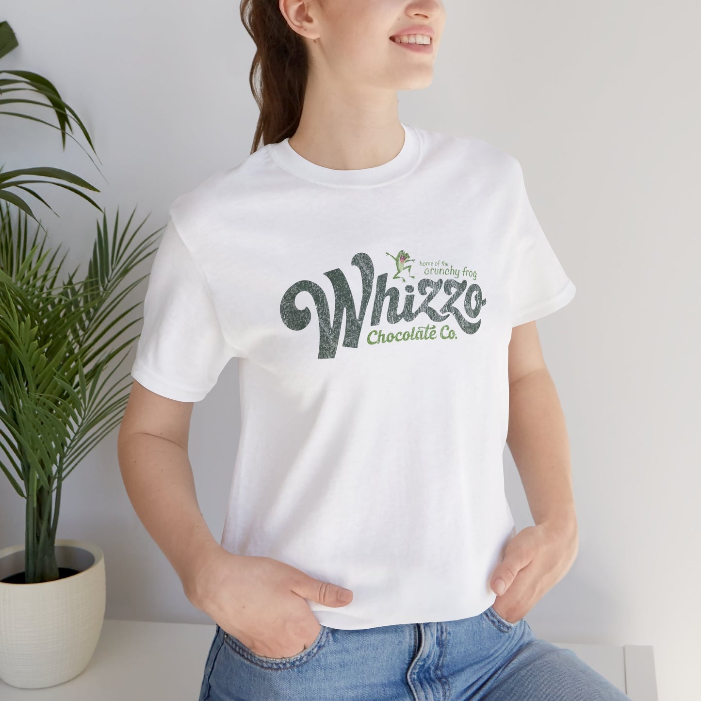 Female wearing white t-shirt with vintage Whizzo Chocolate Co. logo, inspired by Monty Python, featuring “home of the crunchy frog” graphic.