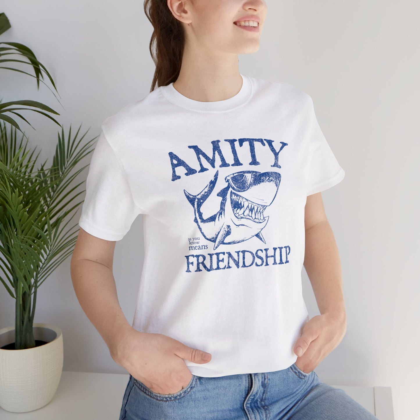 Female wearing white Bella+Canvas t-shirt with a vintage-style Amity Island “Friendship” shark graphic inspired by the movie Jaws