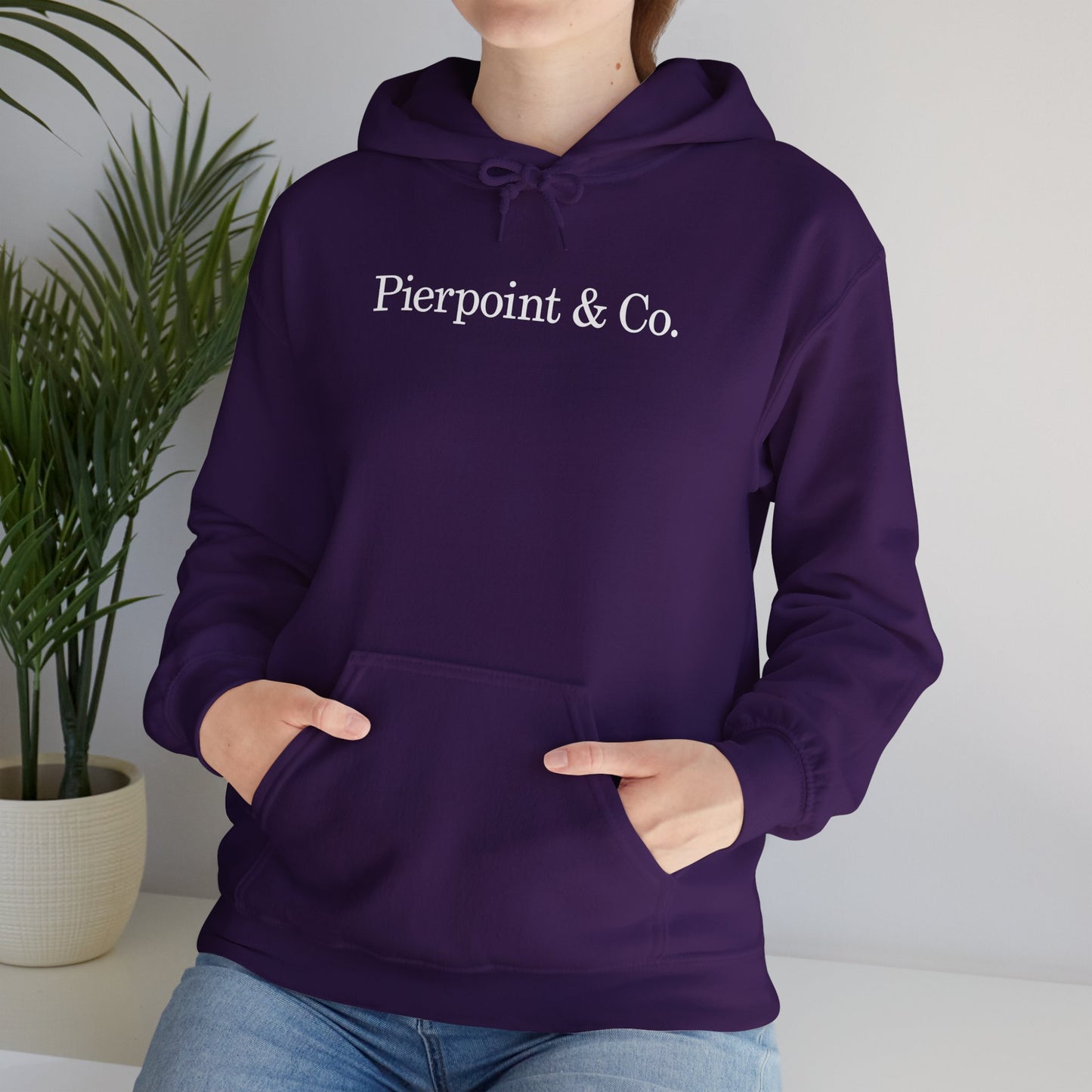 Female model wearing a purple soft Unisex Hoodie Heavy Blend Hooded Sweatshirt featuring the Pierpoint & Co logo worn by the character Eric Tao in the TV show Industry.