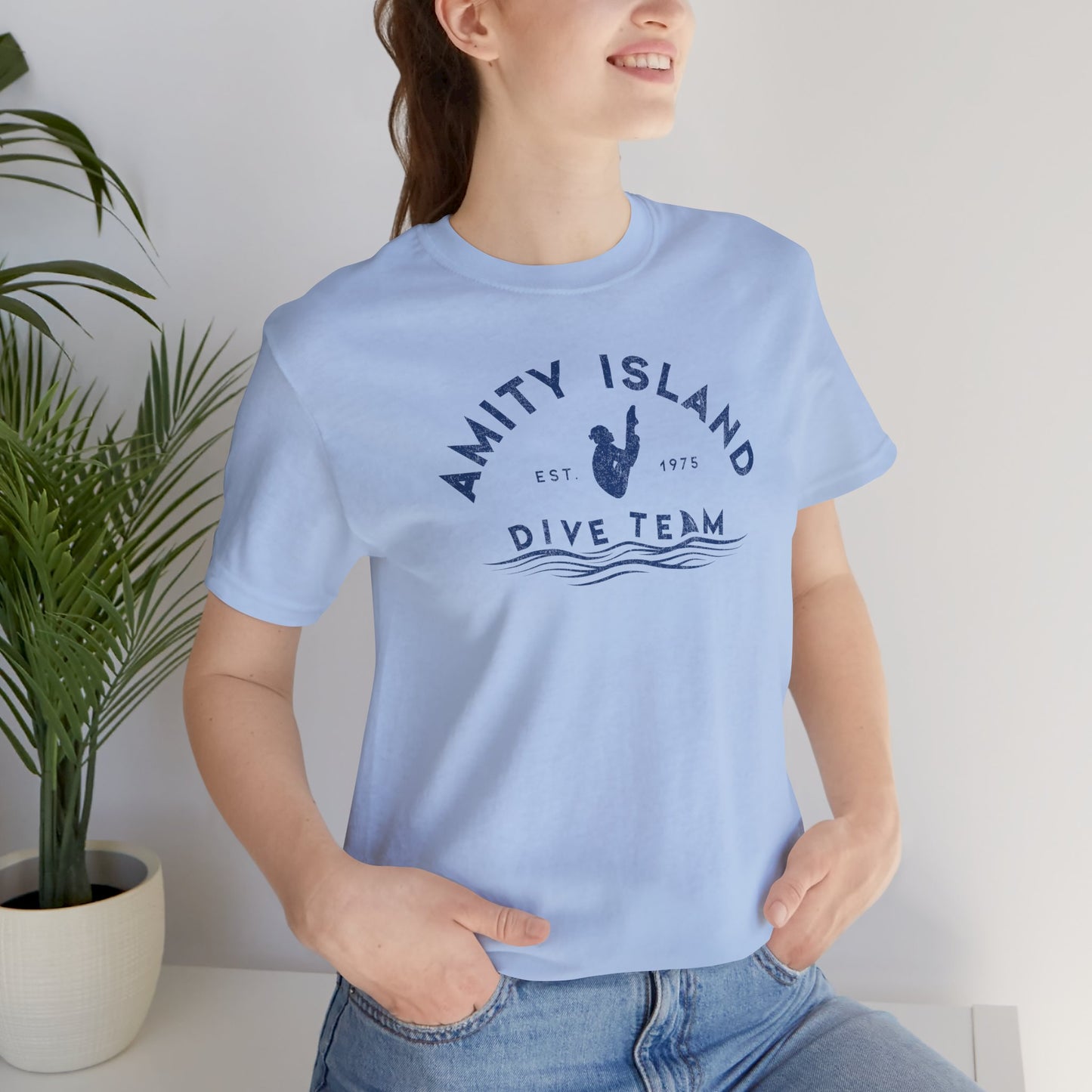 Female wearing baby blue Bella+Canvas t-shirt with vintage-style Amity Island Dive Team logo, inspired by the movie Jaws.
