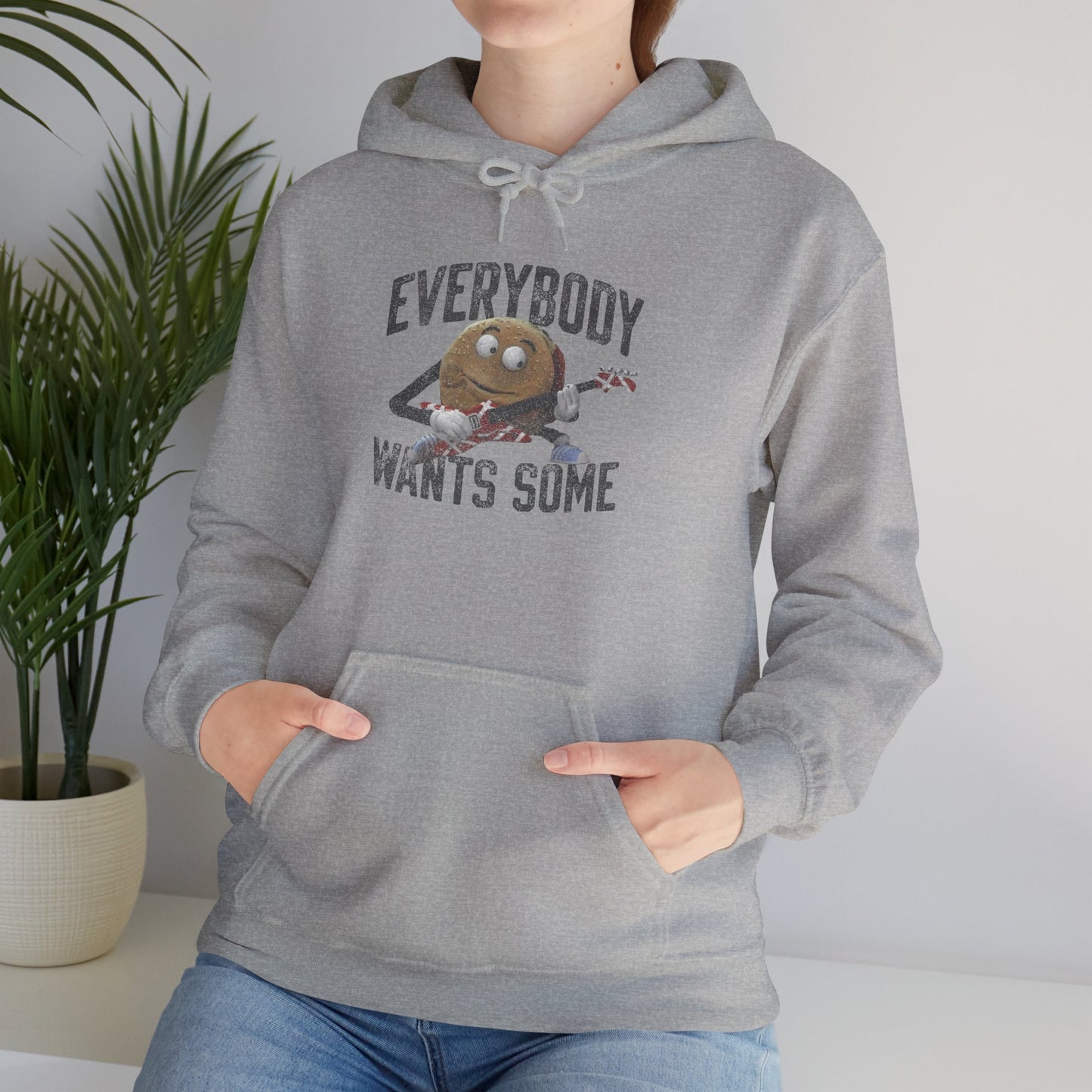 Female model wearing a sport athletic grey colored soft Unisex Hoodie Heavy Blend Hooded Sweatshirt featuring the phrase EVERYBODY WANTS SOME with a graphic of the Van Halen singing hamburger playing guitar from the movie Better Off Dead, designed by ScriptedBrand in a vintage distressed style.