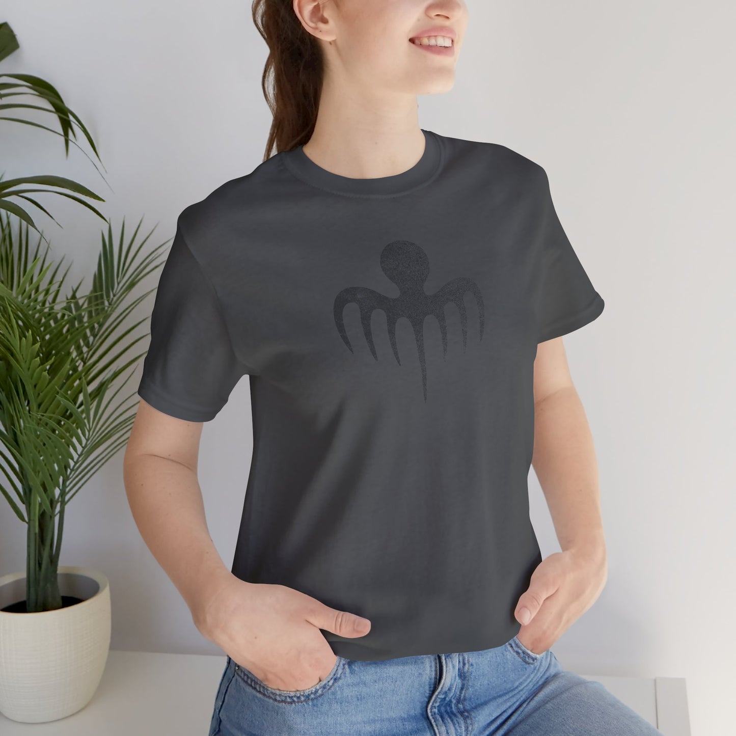 Female model wearing an asphalt grey colored soft Bella+Canvas 3001 short-sleeve t-shirt featuring a logo graphic of the fictional criminal organization Spectre, inspired by the James Bond movie franchise, in a vintage distressed style.