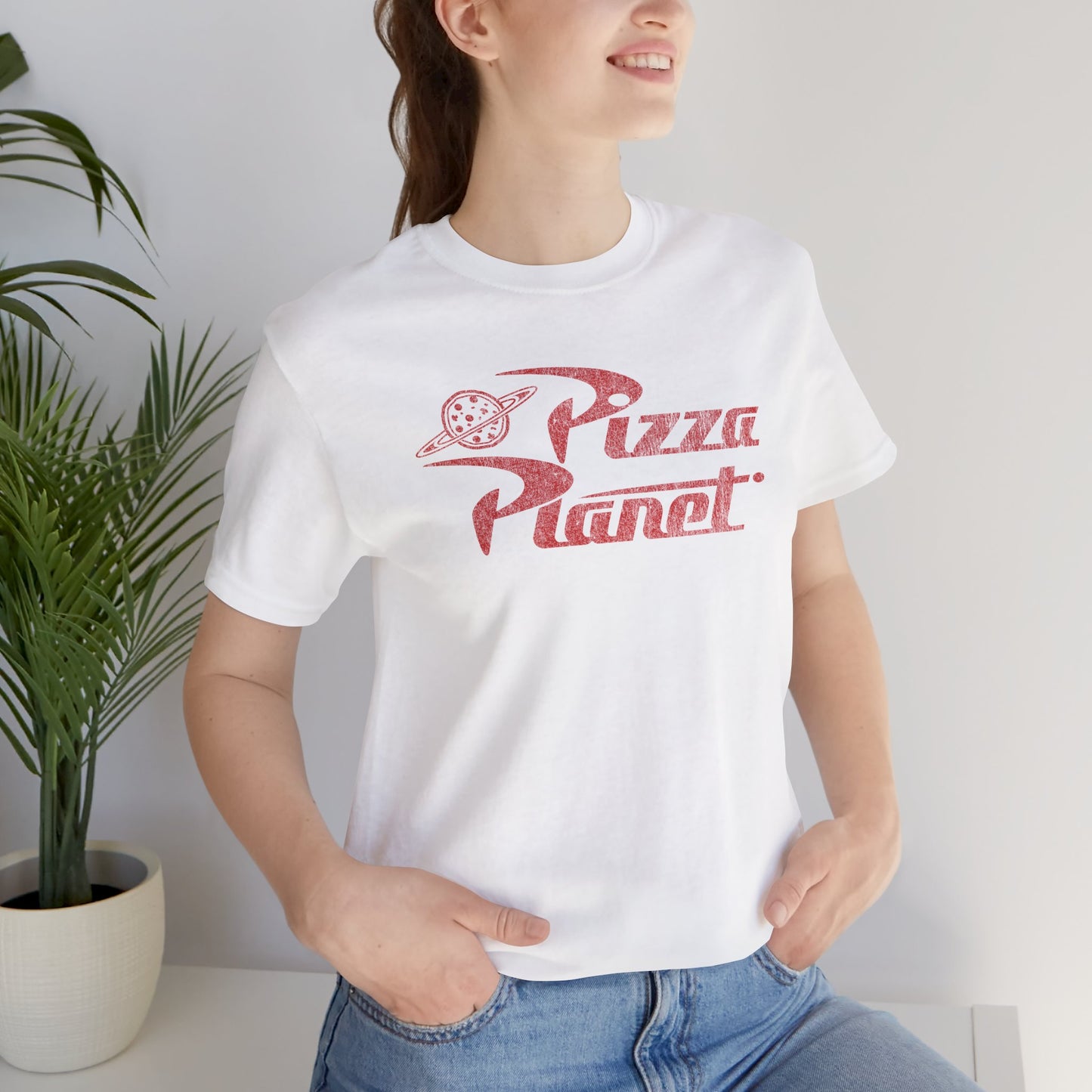 Woman wearing white t-shirt with distressed red Pizza Planet logo inspired by the Toy Story movies.