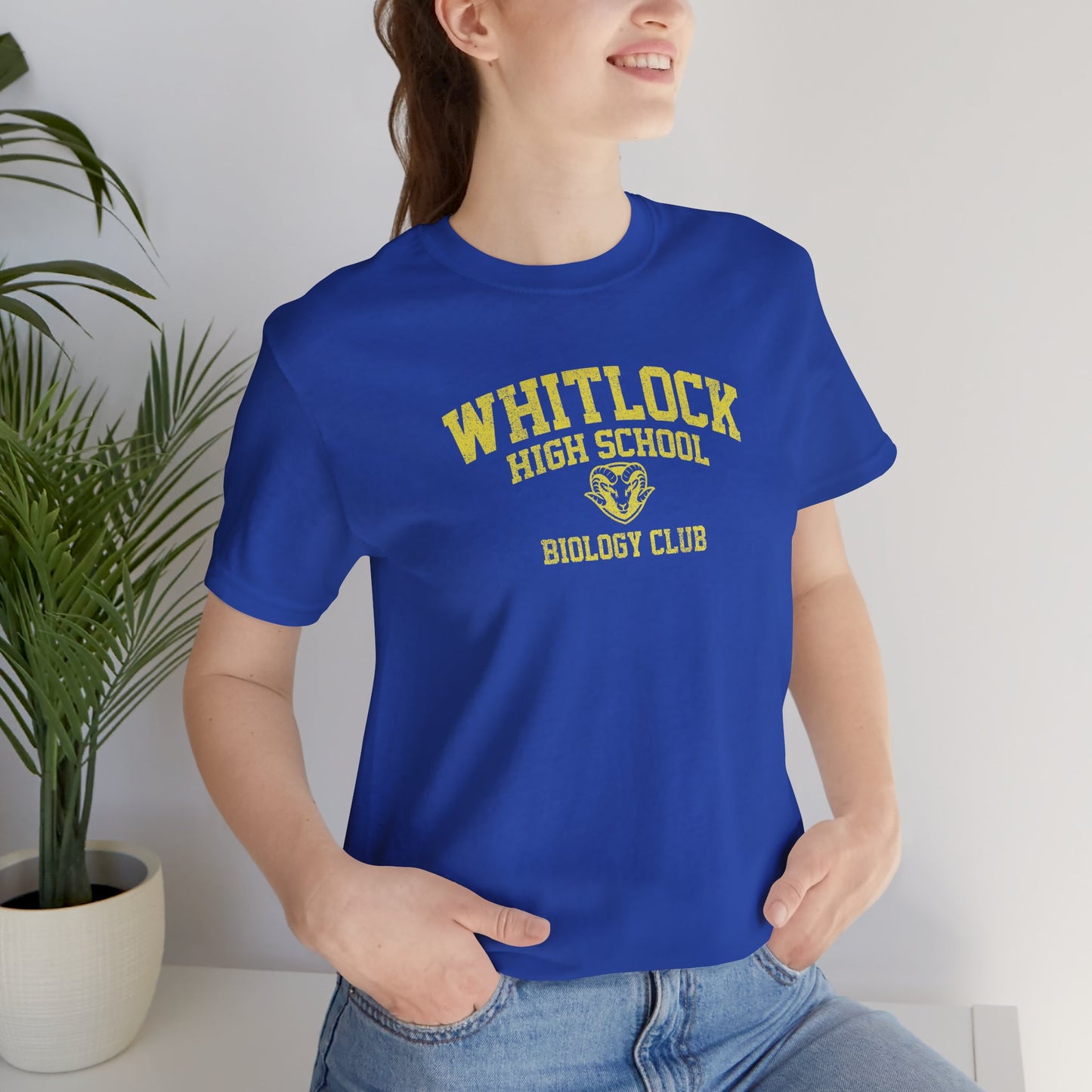 Woman wearing blue t-shirt featuring gold Whitlock High School Rams logo graphic inspired by the TV show AP Bio in a vintage style.