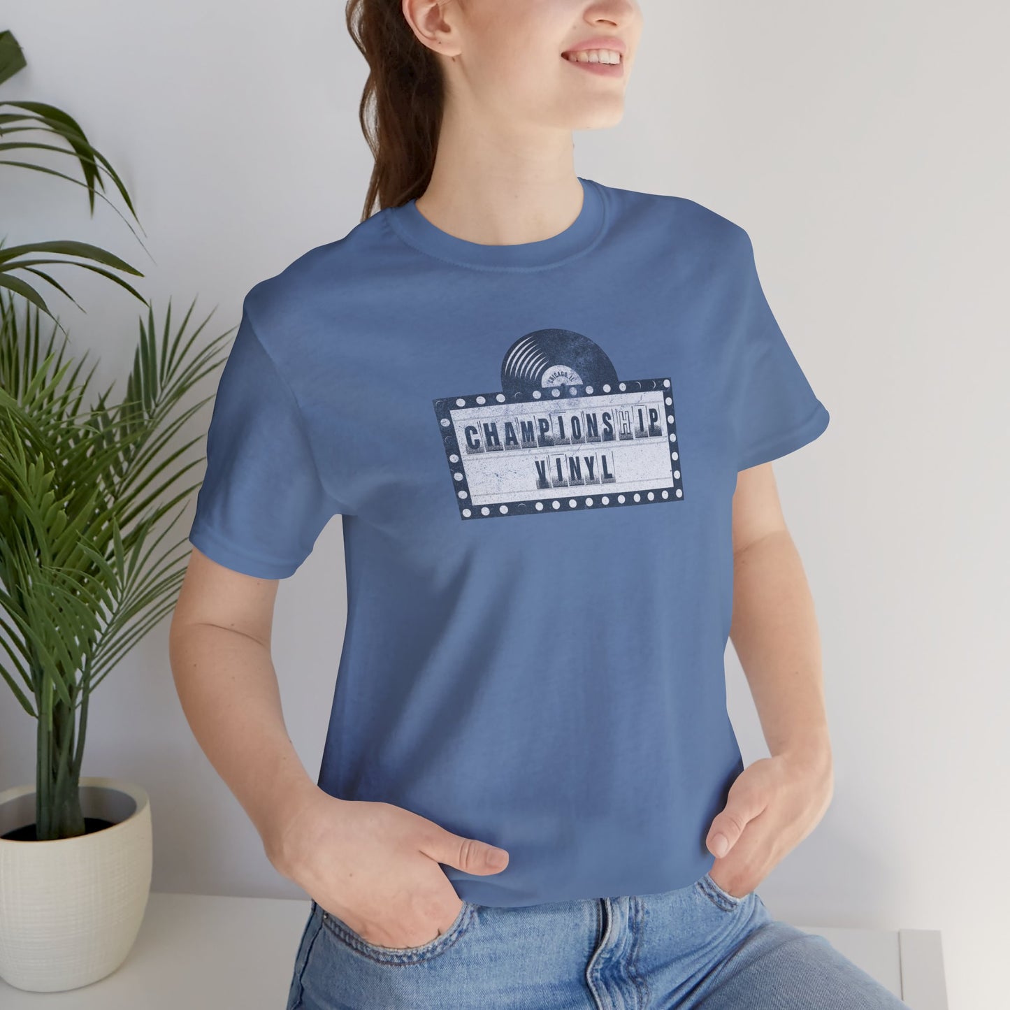 Female wearing blue t-shirt featuring the fictional logo CHAMPIONSHIP VINYL record store from movie High Fidelity in a vintage distressed style.