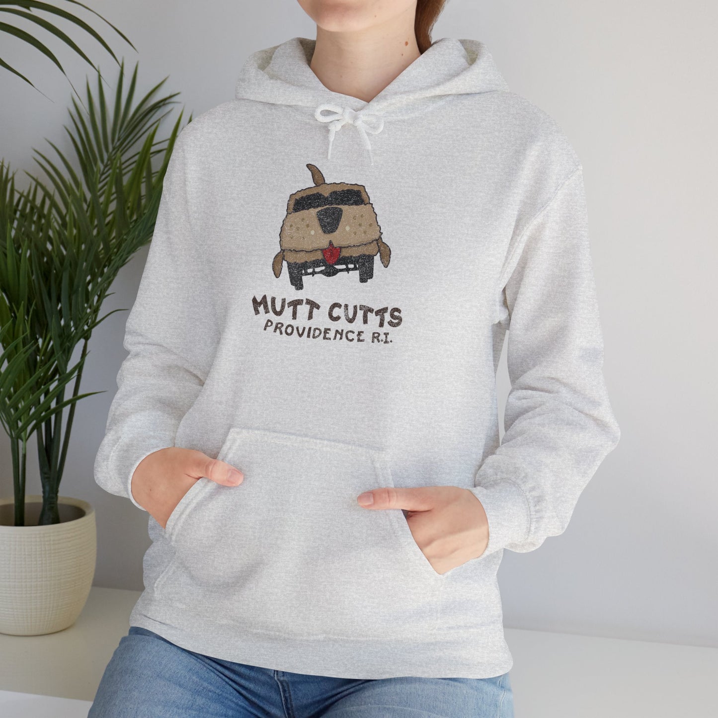 Female model wearing an ash grey colored soft Unisex Hoodie Heavy Blend Hooded Sweatshirt featuring a Mutt Cutts logo graphic inspired by the movie Dumb and Dumber, illustrated by ScriptedBrand in a vintage distressed style.