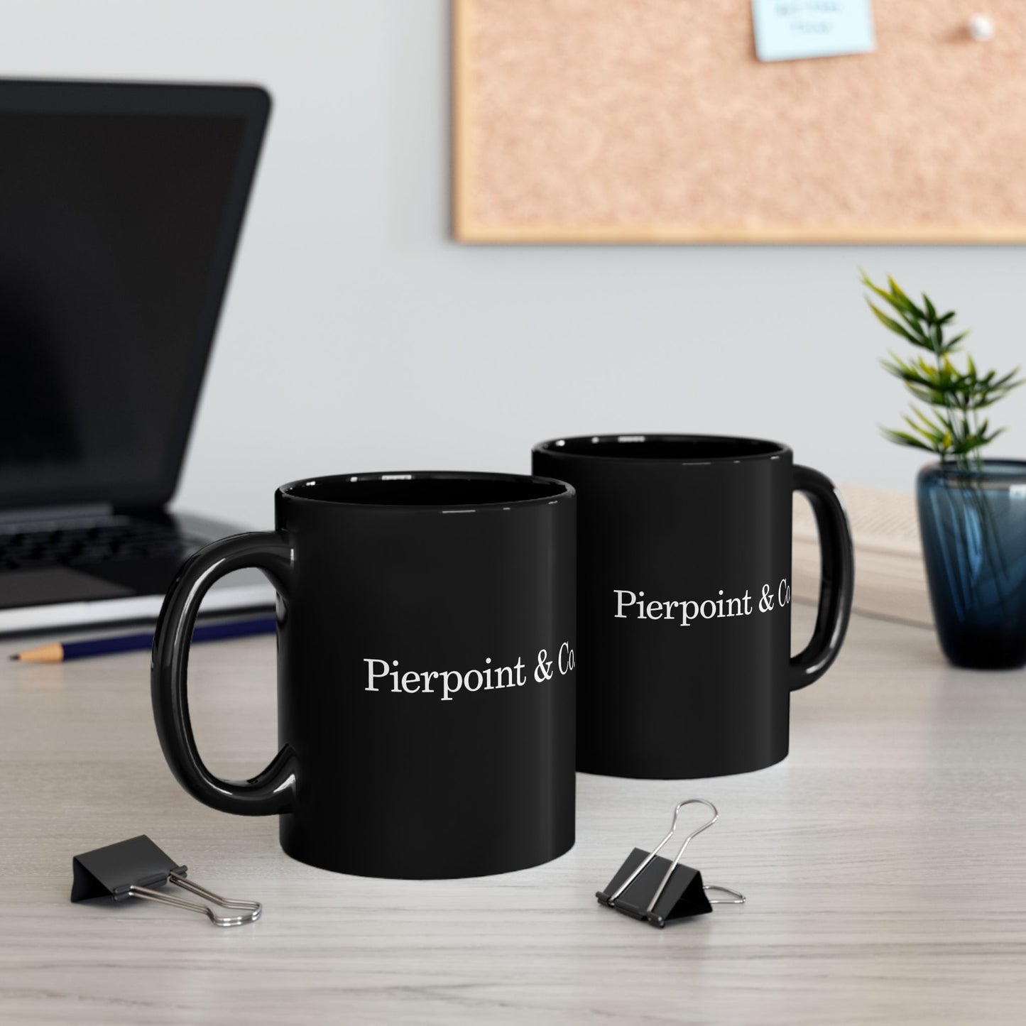 Two 11 oz black mugs with 'Pierpoint & Co' on a desk with office supplies and decor.