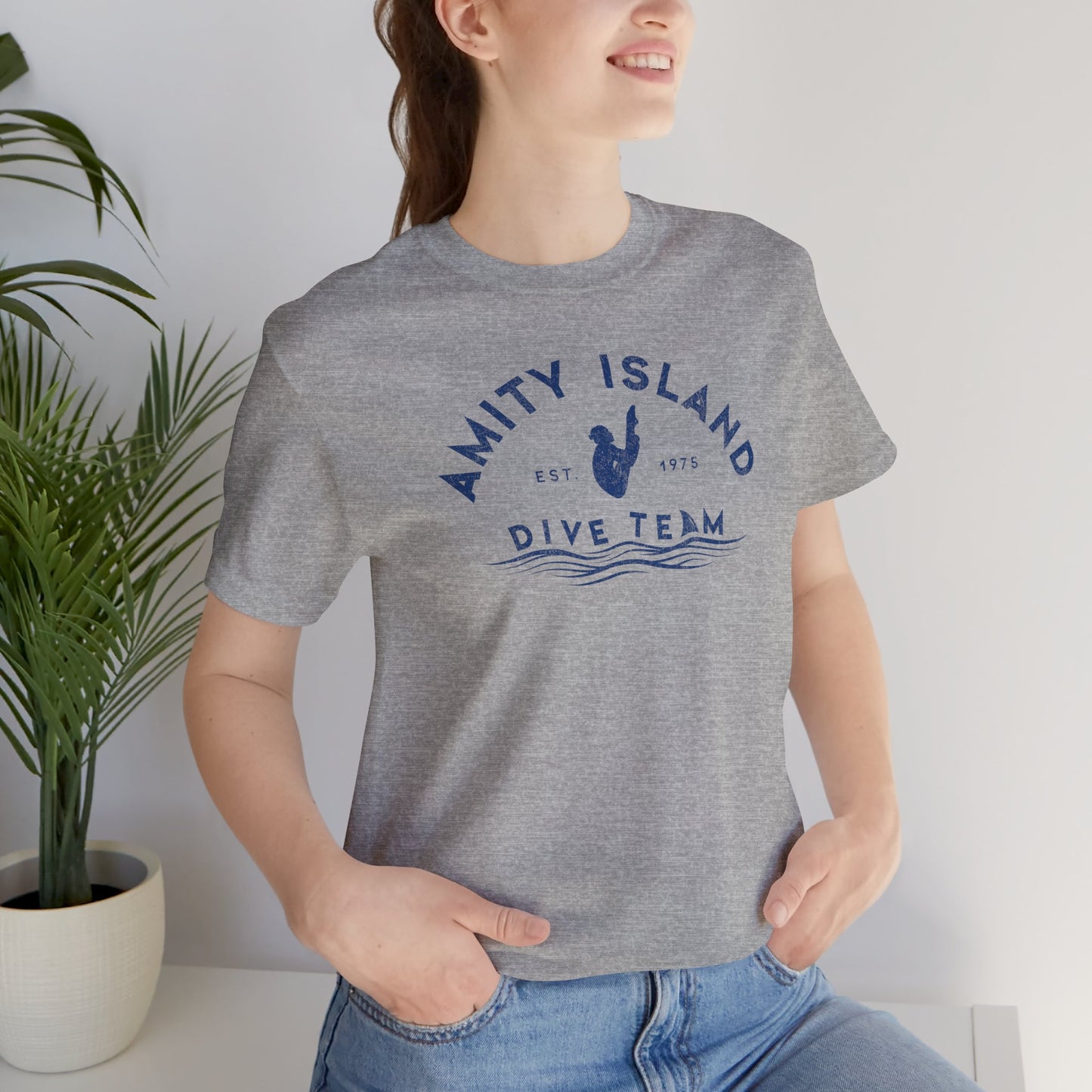 Female wearing athletic heather grey Bella+Canvas t-shirt with vintage-style Amity Island Dive Team logo, inspired by the movie Jaws.