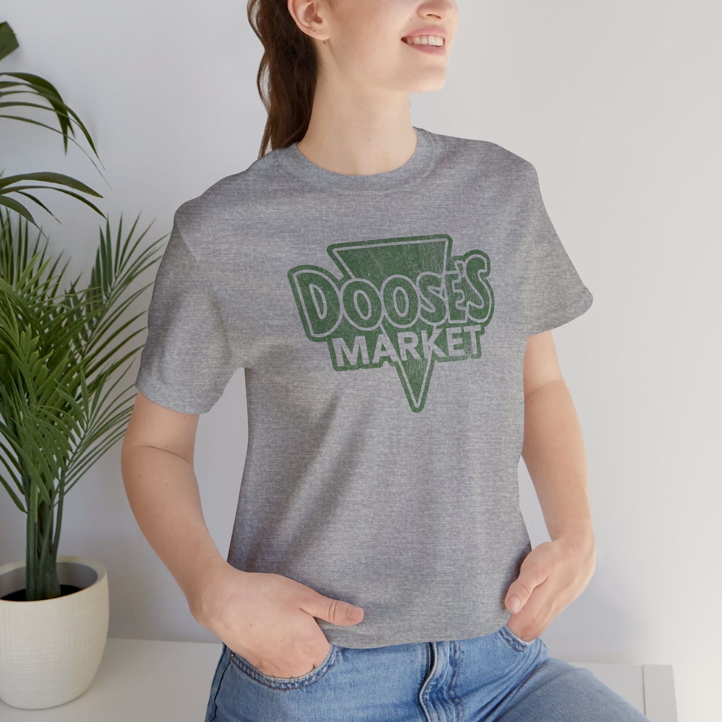 female wearing heather gray Bella+Canvas t-shirt with a vintage-style Doose’s Market logo graphic, inspired by Gilmore Girls