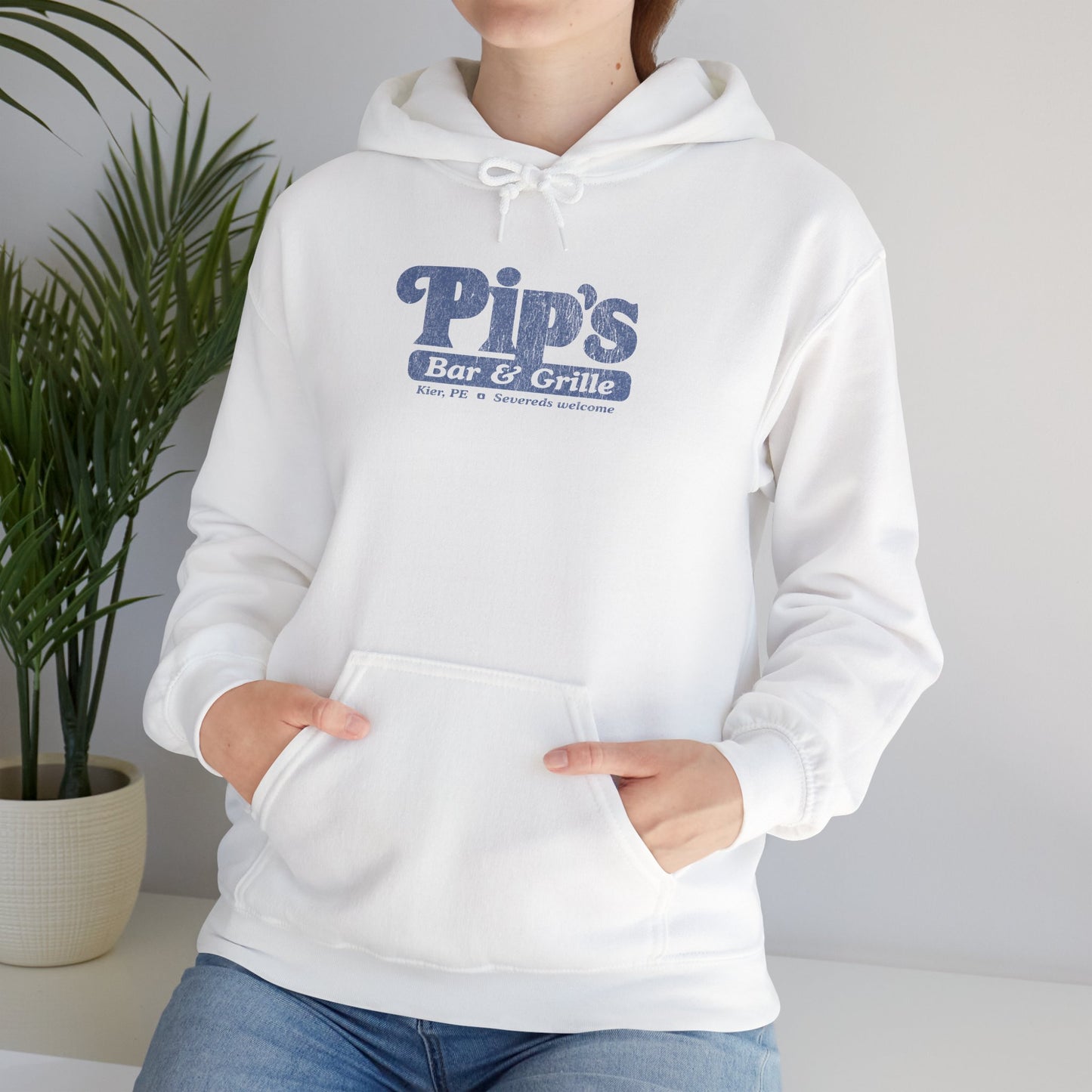 Female model wearing a white colored Soft Unisex Hoodie Heavy Blend Hooded Sweatshirt featuring the Pips Bar & Grill logo, with the added text "Severeds Welcome" inspired by the TV show Severance in a vintage distressed style, sold by ScriptedBrand.
