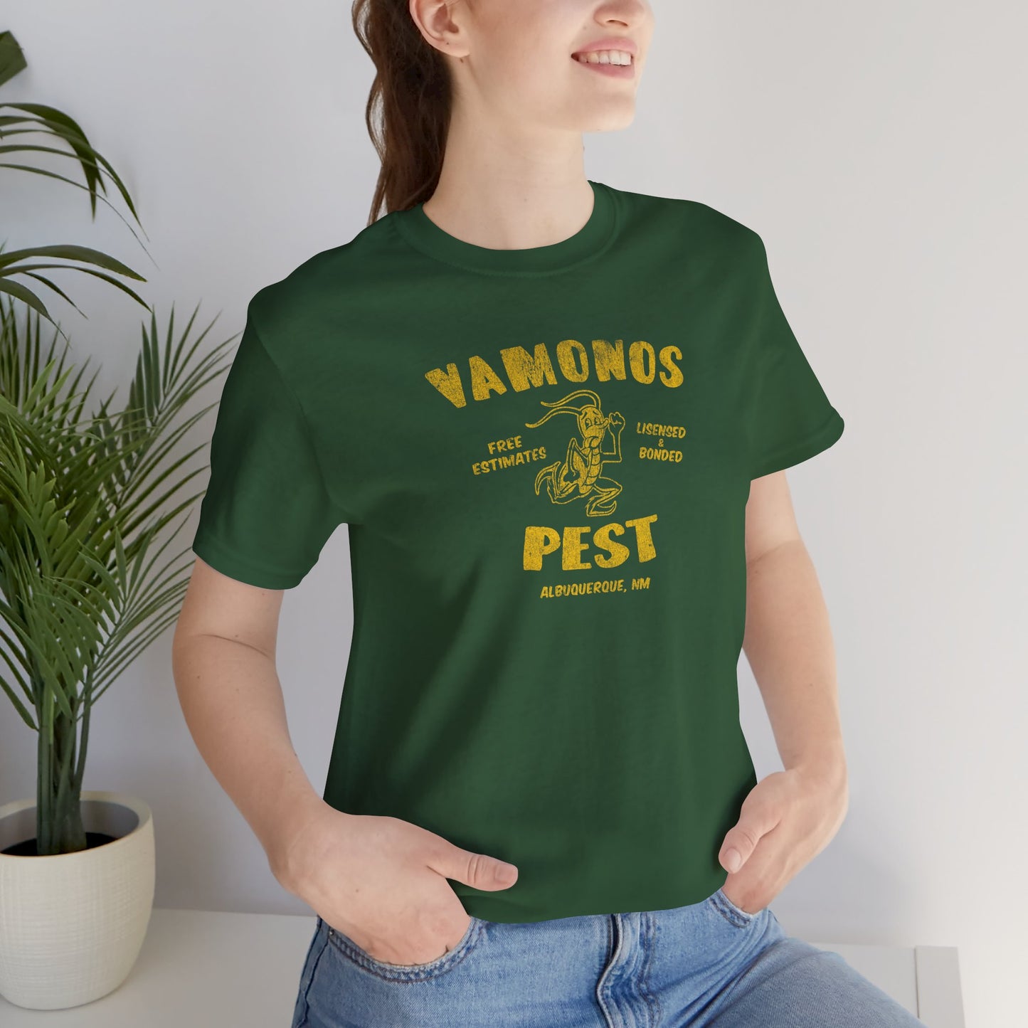Female model wearing an evergreen colored soft Bella+Canvas 3001 short-sleeve t-shirt featuring the Vamonos Pest Exterminators logo from the TV show Breaking Bad in a vintage distressed style, sold by ScriptedBrand.