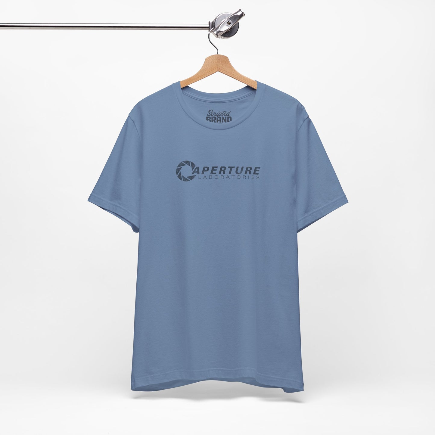 Steel blue colored soft Bella+Canvas t-shirt on a hanger with the Aperture Laboratories logo from the video game Portal and Portal 2 in a vintage ink-stamped distressed style.