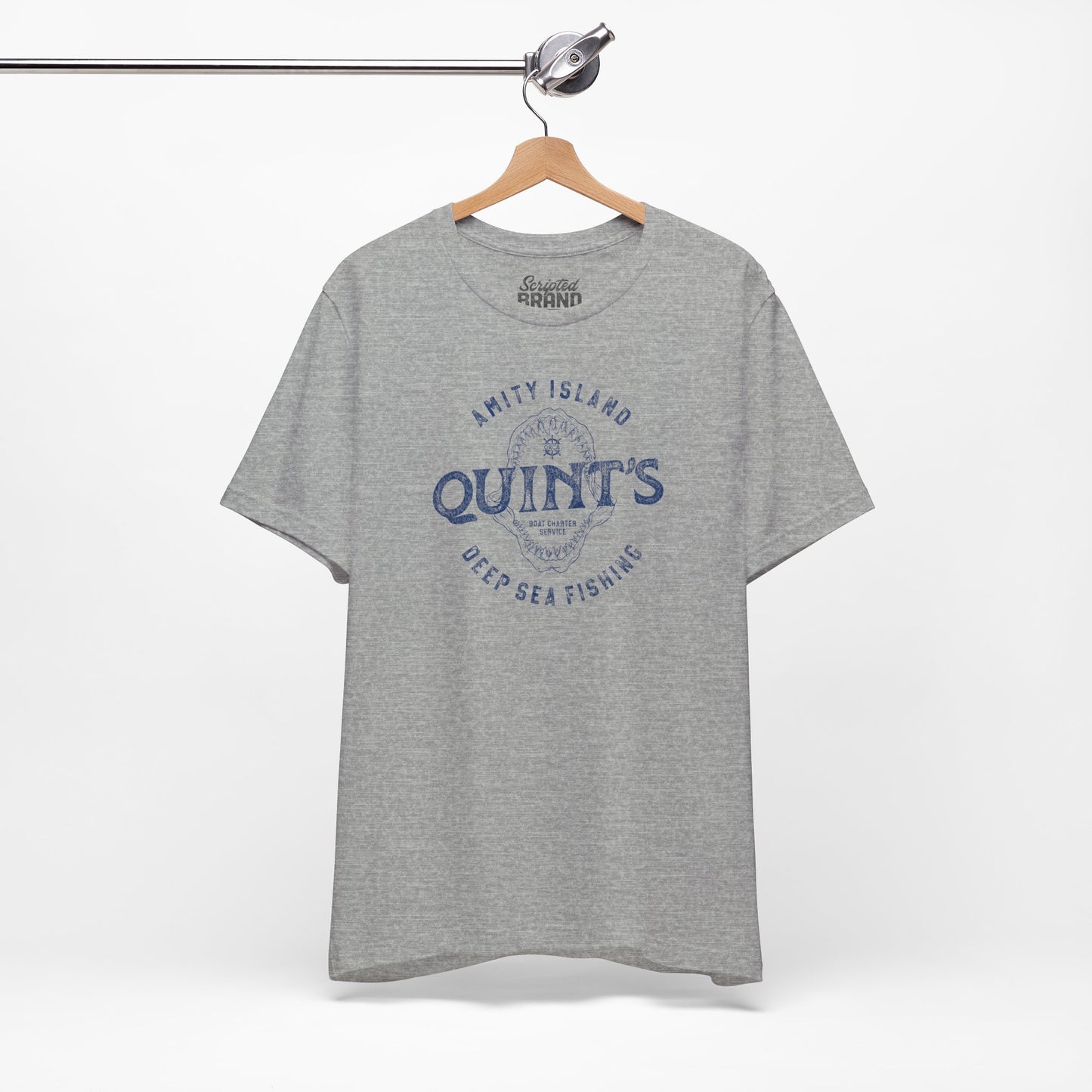 Athletic Heather Gray colored Soft short-sleeve t-shirt on a hanger featuring the Quint's Deep Sea Fishing Boat Charters logo graphic inspired by the movie Jaws in a vintage distressed ink-stamped worn-in style.