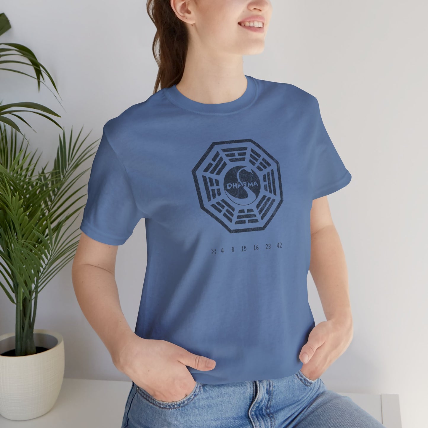 Female model wearing Lavender blue short-sleeve t-shirt featuring the Dharma Initiative swan station logo graphic from the TV show LOST in a vintage distressed style.