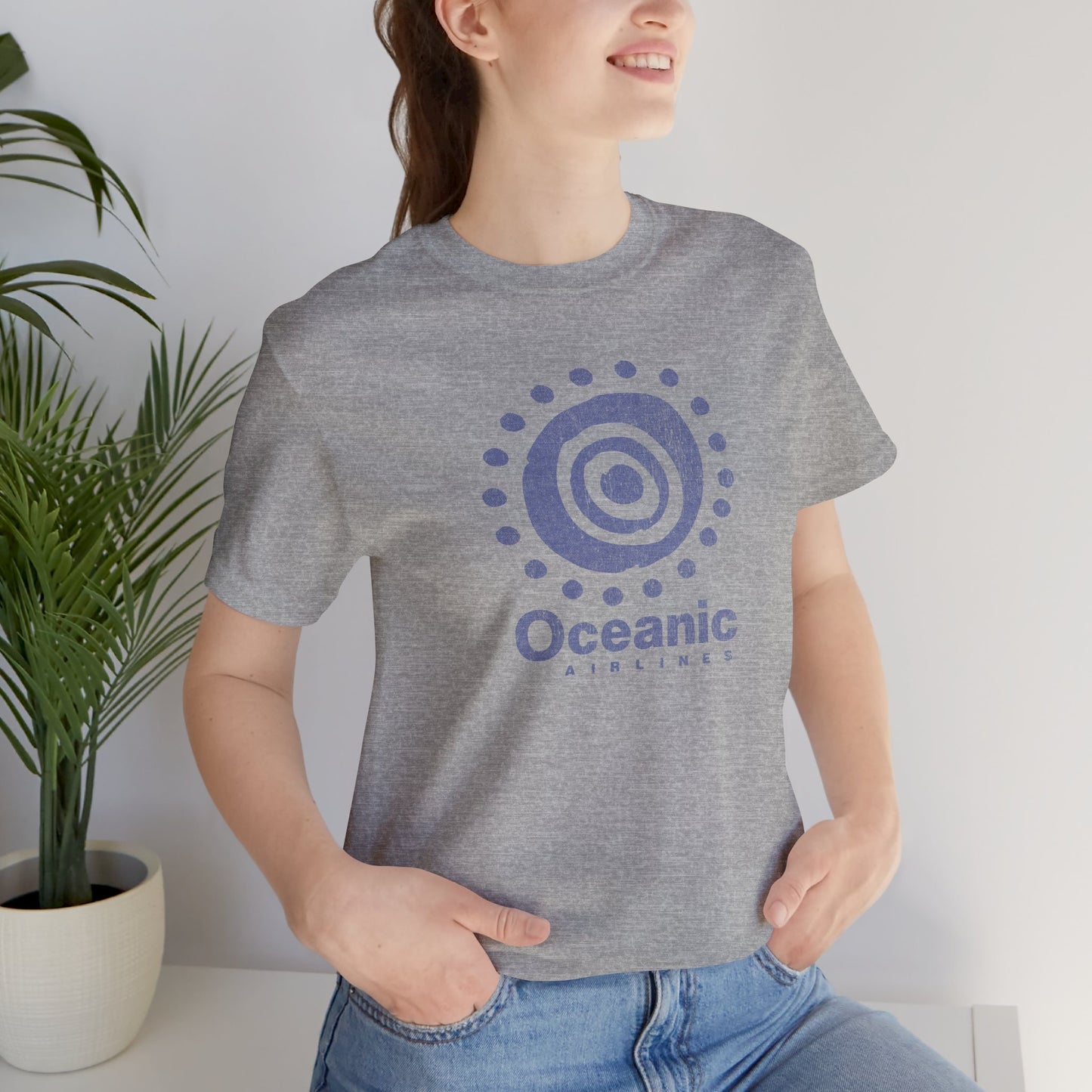 Woman wearing heather gray t-shirt featuring the Oceanic Airlines logo graphic from the TV show LOST in a vintage distressed style.
