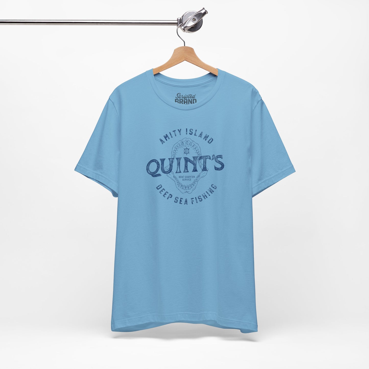 Ocean blue colored Soft short-sleeve t-shirt on a hanger featuring the Quint's Deep Sea Fishing Boat Charters logo graphic inspired by the movie Jaws in a vintage distressed ink-stamped worn-in style.