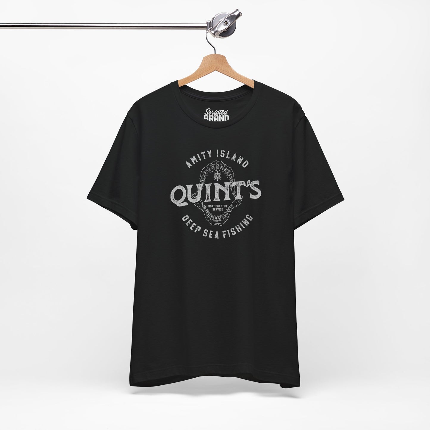 Black colored Soft short-sleeve t-shirt on a hanger featuring the Quint's Deep Sea Fishing Boat Charters logo graphic inspired by the movie Jaws in a vintage distressed ink-stamped worn-in style.