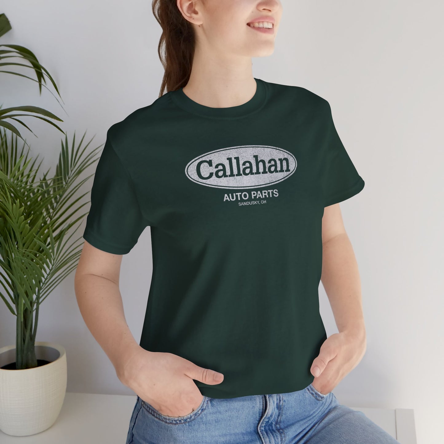 Female model wearing a Forest Green colored soft short-sleeve t-shirt with the Callahan Auto Parts logo from the movie Tommy Boy in a vintage distressed style.