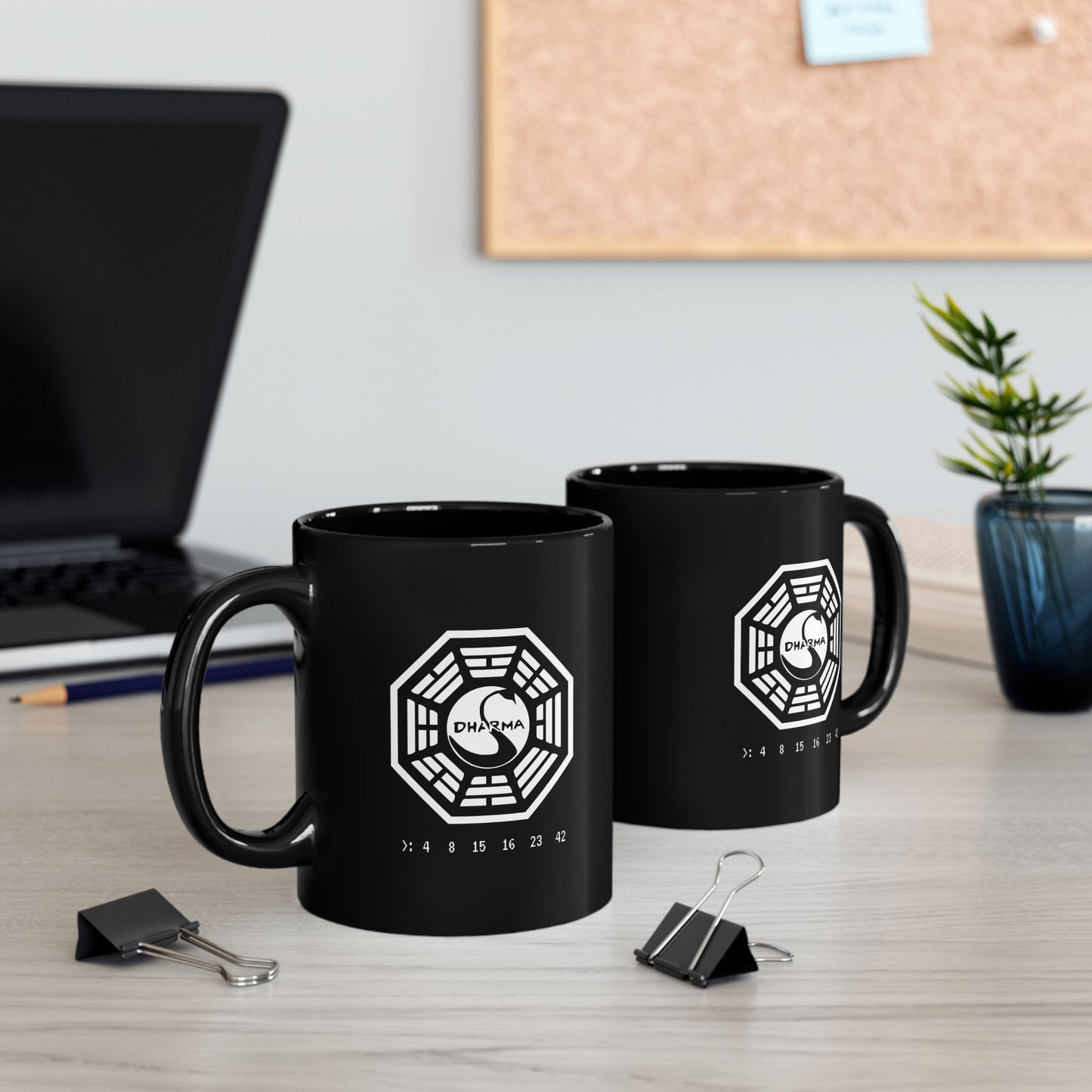 2 Black Ceramic 11 oz Mugs on a desk featuring the Dharma Initiative swan station logo from the TV show LOST, including the Hatch numbers 4 8 15 16 23 42. Graphic is printed white on both sides.