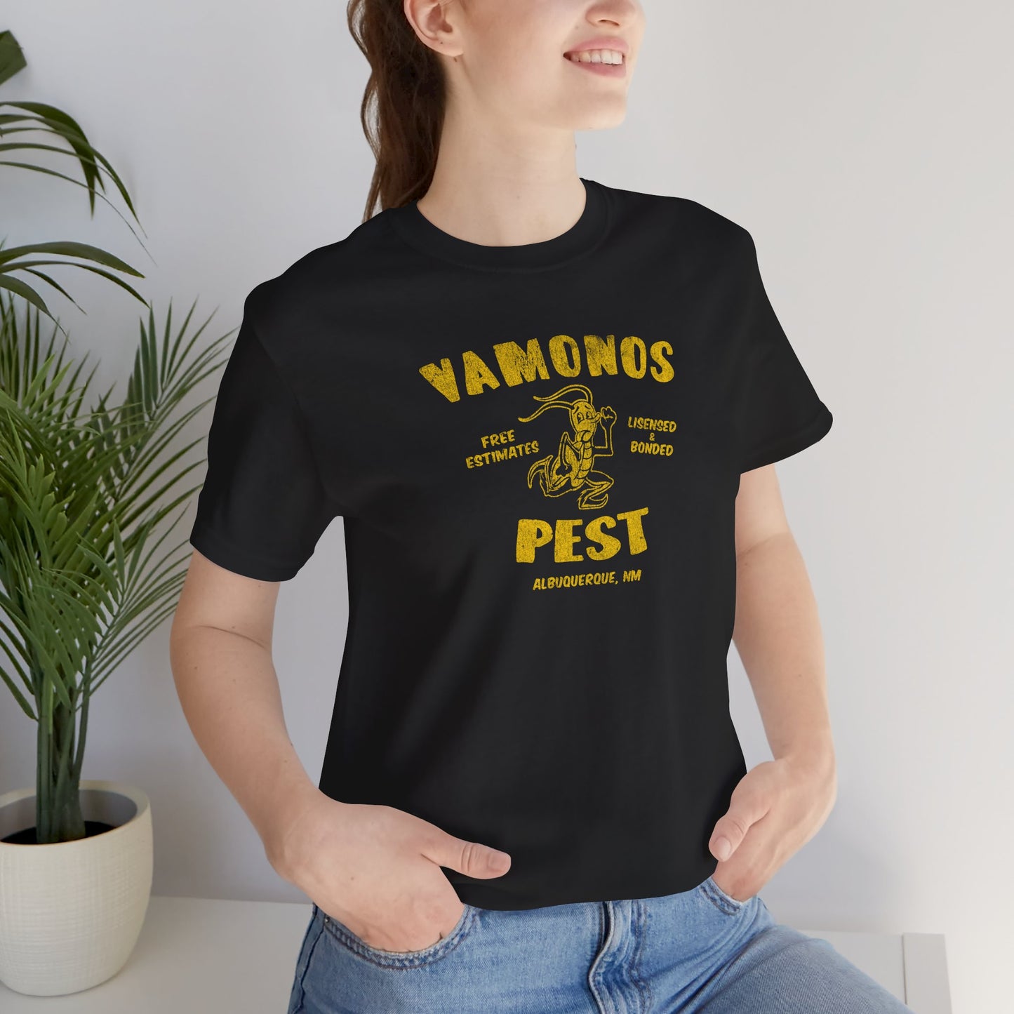 Female model wearing a black colored soft Bella+Canvas 3001 short-sleeve t-shirt featuring the Vamonos Pest Exterminators logo from the TV show Breaking Bad in a vintage distressed style, sold by ScriptedBrand.