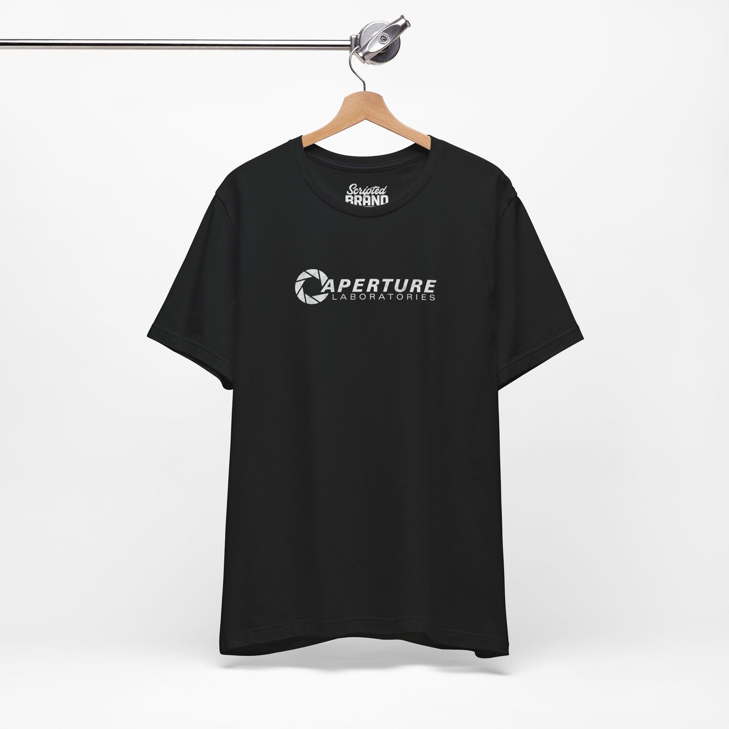 Black colored soft Bella+Canvas t-shirt on a hanger with the Aperture Laboratories logo from the video game Portal and Portal 2 in a vintage ink-stamped distressed style.