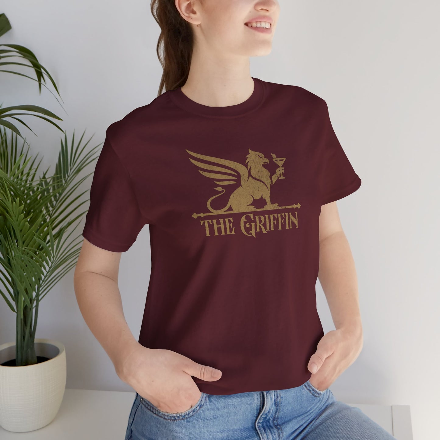Woman wearing maroon t-shirt featuring gold 'The Griffin' Bar logo inspired by the TV show New Girl in a vintage distressed style.