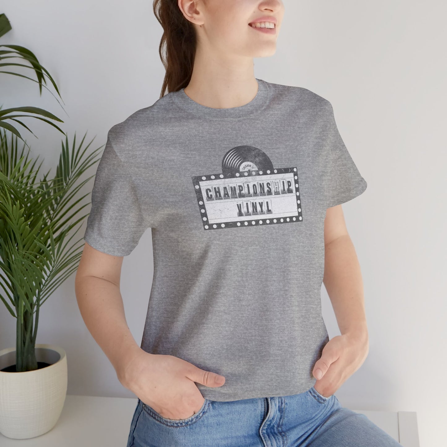 Female wearing grey t-shirt featuring the fictional logo CHAMPIONSHIP VINYL record store from movie High Fidelity in a vintage distressed style.