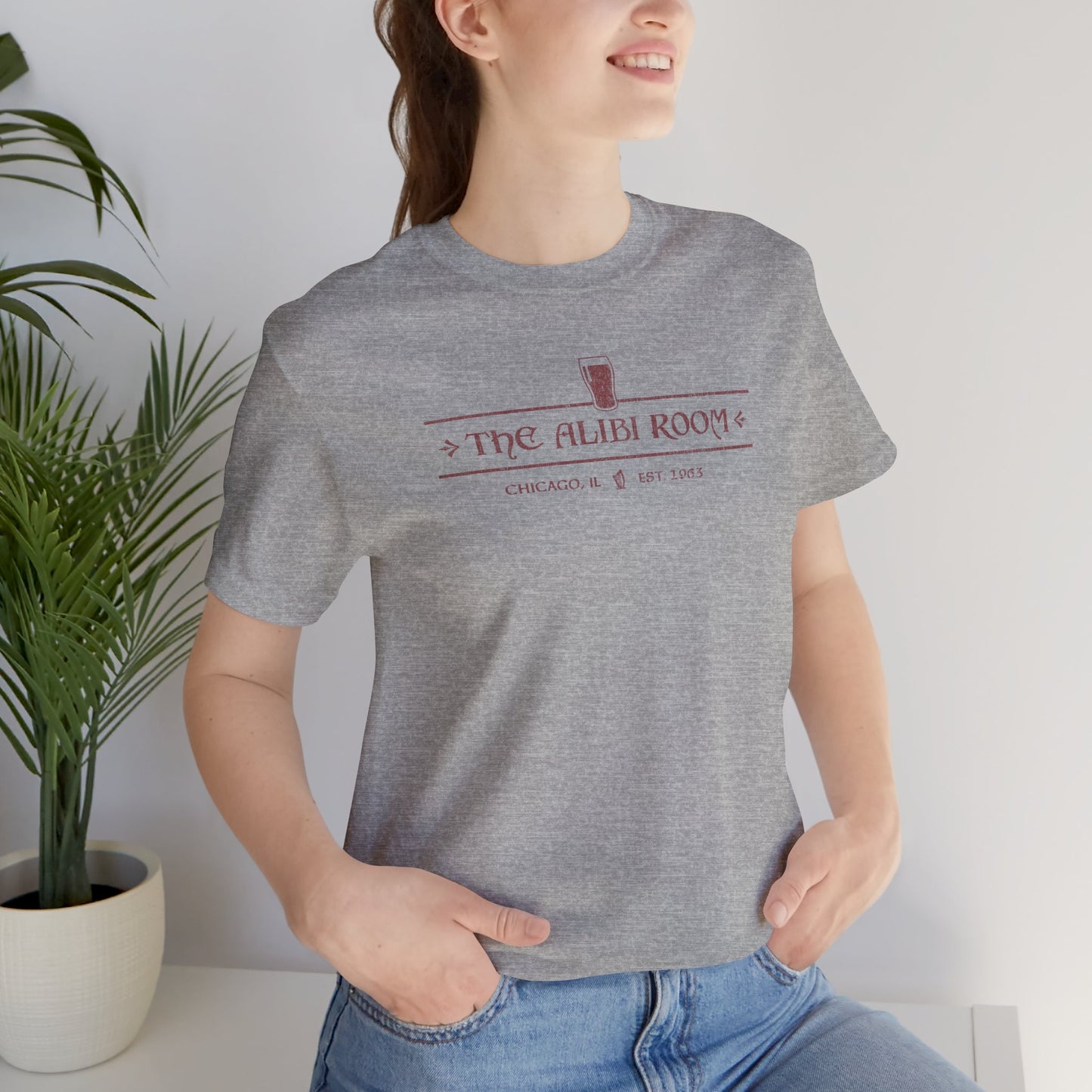 Woman wearing heather gray t-shirt featuring The Alibi Room logo graphic inspired by the TV show Shameless in a vintage distressed style.