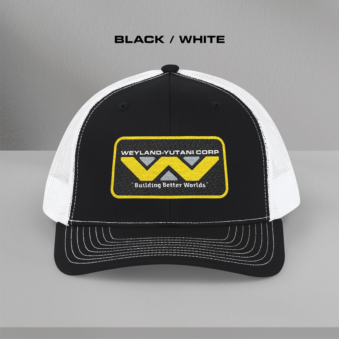 Front view of black-white Embroidered Snapback Trucker Cap with logo of Weyland-Yutani from the Alien movie franchise.