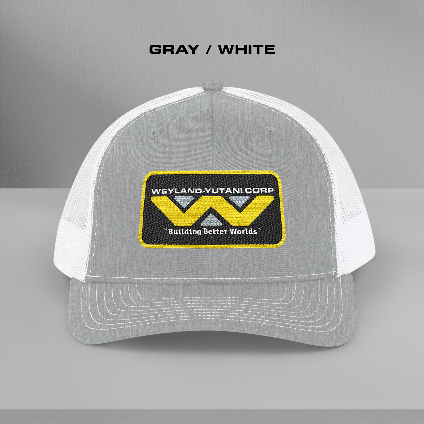 Front view of gray-white Embroidered Snapback Trucker Cap with logo of Weyland-Yutani from the Alien movie franchise.