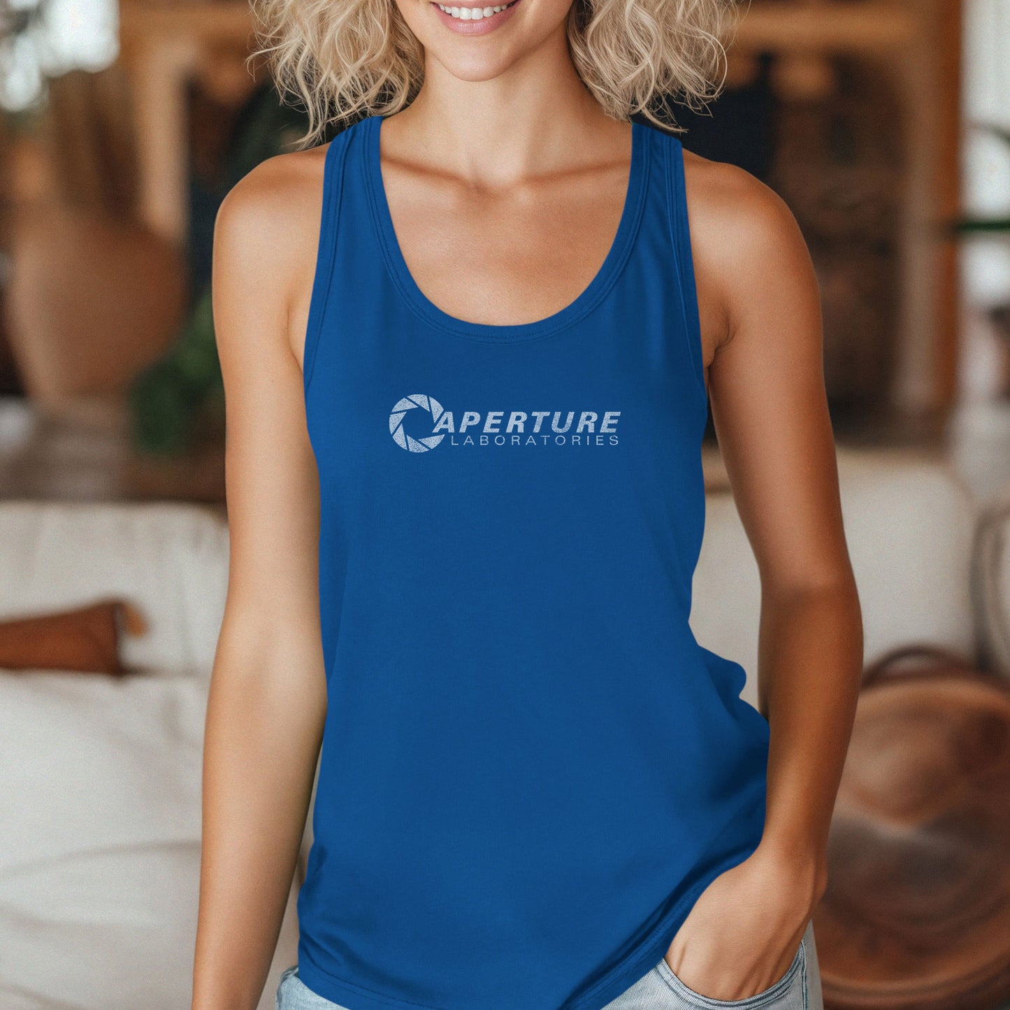 Female model wearing a royal blue colored Women's Racerback Tank Top Shirt featuring the Aperture Laboratories logo from the video games Portal and Portal 2 in a vintage distressed style, sold by ScriptedBrand.