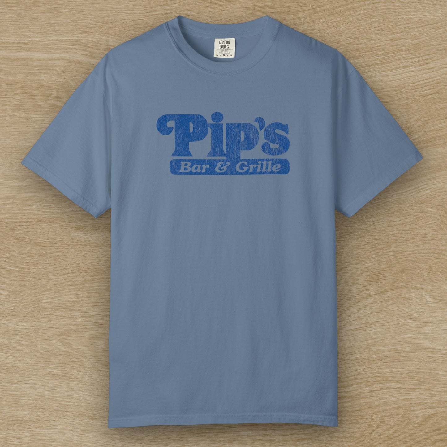 Vintage-style Pip’s Bar & Grill t-shirt from Severance on Comfort Colors 1717 in the color blue jean, blue distressed logo.