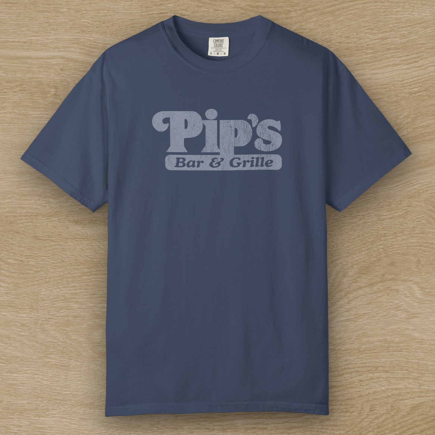 Vintage-style Pip’s Bar & Grill t-shirt from Severance on Comfort Colors 1717 in the color midnight, distressed logo.