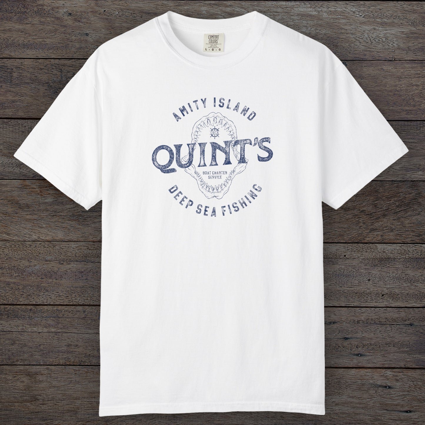 White Comfort Colors t-shirt with vintage Quint’s Deep Sea Fishing logo from Jaws, featuring shark graphic, distressed style.