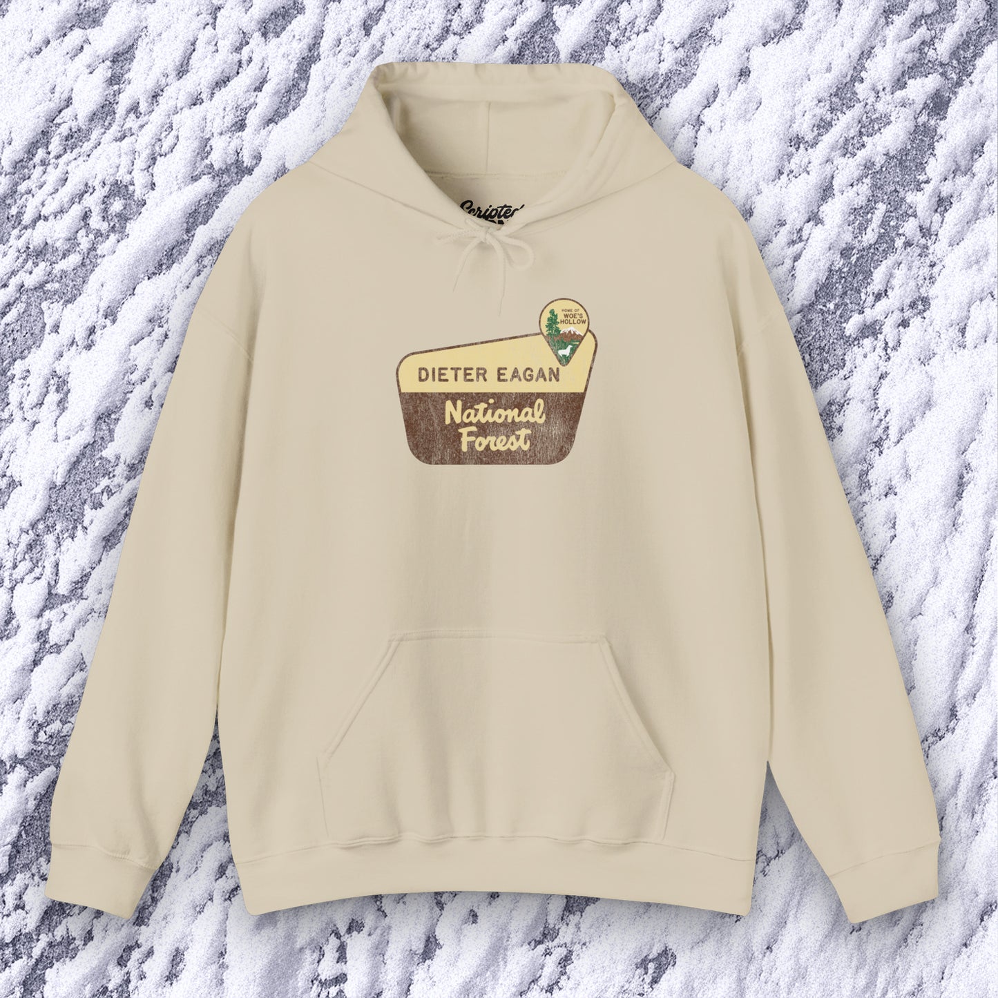 Mockup of a sand colored Soft Unisex Hoodie Heavy Blend Hooded Sweatshirt featuring the logo graphic of the Dieter Eagan National Forest inspired by the TV show Severance in a vintage distressed ink-stamped worn-in style.