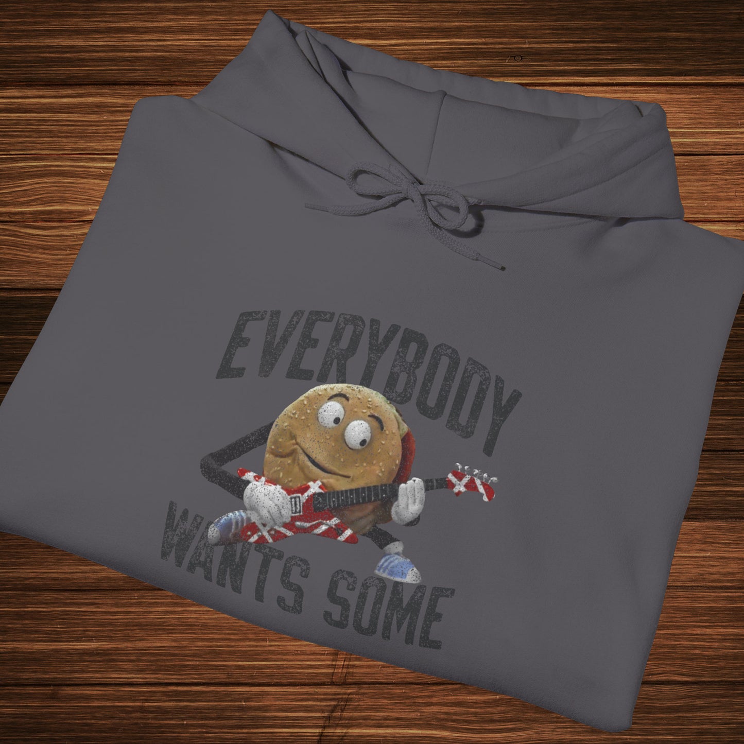 Folded charcoal grey colored soft Unisex Hoodie Heavy Blend Hooded Sweatshirt featuring the phrase EVERYBODY WANTS SOME with a graphic of the Van Halen singing hamburger playing guitar from the movie Better Off Dead, designed by ScriptedBrand in a vintage distressed style.