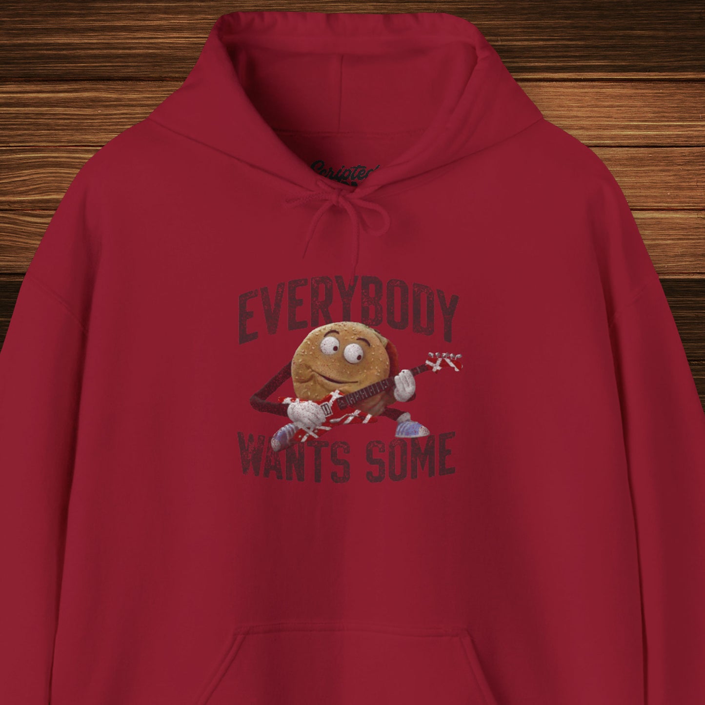Front view of a cardinal red colored soft Unisex Hoodie Heavy Blend Hooded Sweatshirt featuring the phrase EVERYBODY WANTS SOME with a graphic of the Van Halen singing hamburger playing guitar from the movie Better Off Dead, designed by ScriptedBrand in a vintage distressed style.