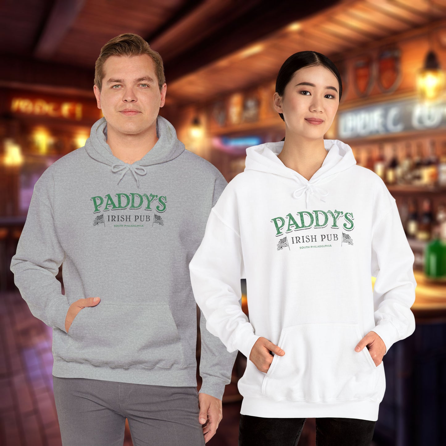 2 models wearing a sport heather grey and white colored soft unisex Hoodie Heavy Blend Hooded Sweatshirts featuring the green Paddy's Pub logo graphic from the TV Show It's Always Sunny in Philadelphia, in a vintage distressed style, sold by ScriptedBrand.