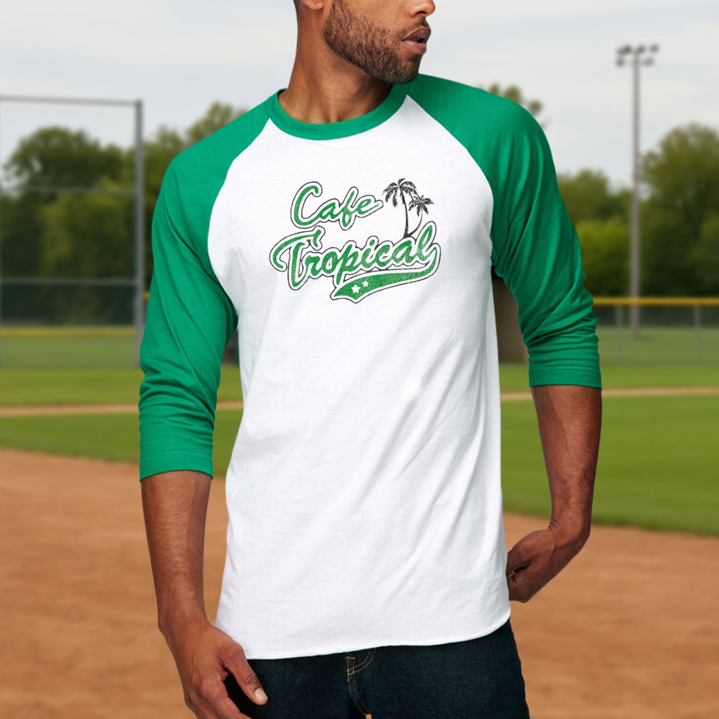 Male model wearing a white and Green colored soft raglan 3/4 sleeve Tultex 245 baseball shirt featuring the fictional Cafe Tropical logo that David wore in the TV Show Schitts Creek in a vintage distressed style, sold by ScriptedBrand.