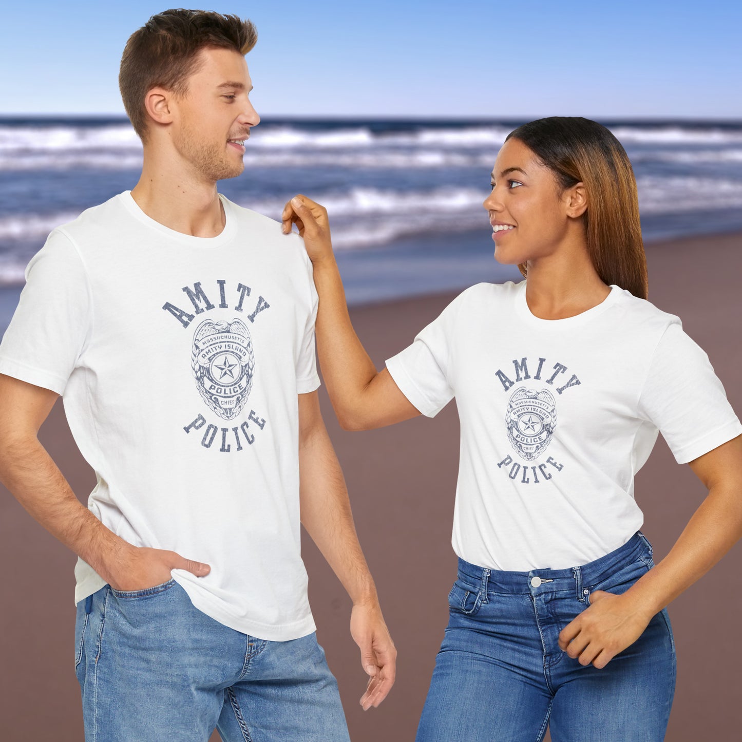 2 models wearing white colored Soft unisex Bella+Canvas 3001 short-sleeve t-shirts featuring an Amity Island Police logo graphic, designed by ScriptedBrand, and inspired by the movie Jaws in a vintage distressed style.