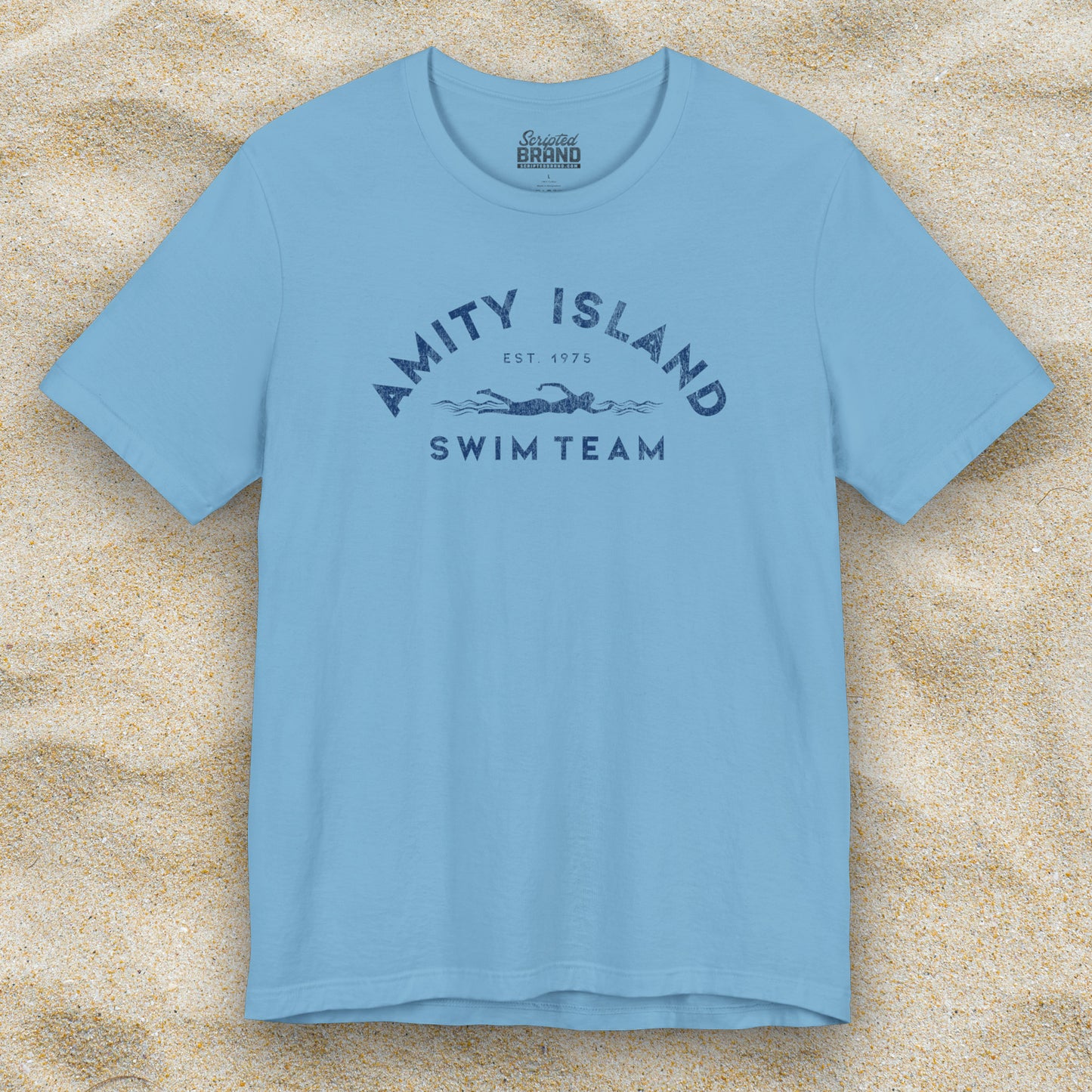 Front view of an Ocean Blue colored Soft unisex Bella+Canvas 3001 short-sleeve t-shirt featuring an Amity Island Swim Team logo graphic, designed by ScriptedBrand, and inspired by the movie Jaws in a vintage distressed style.